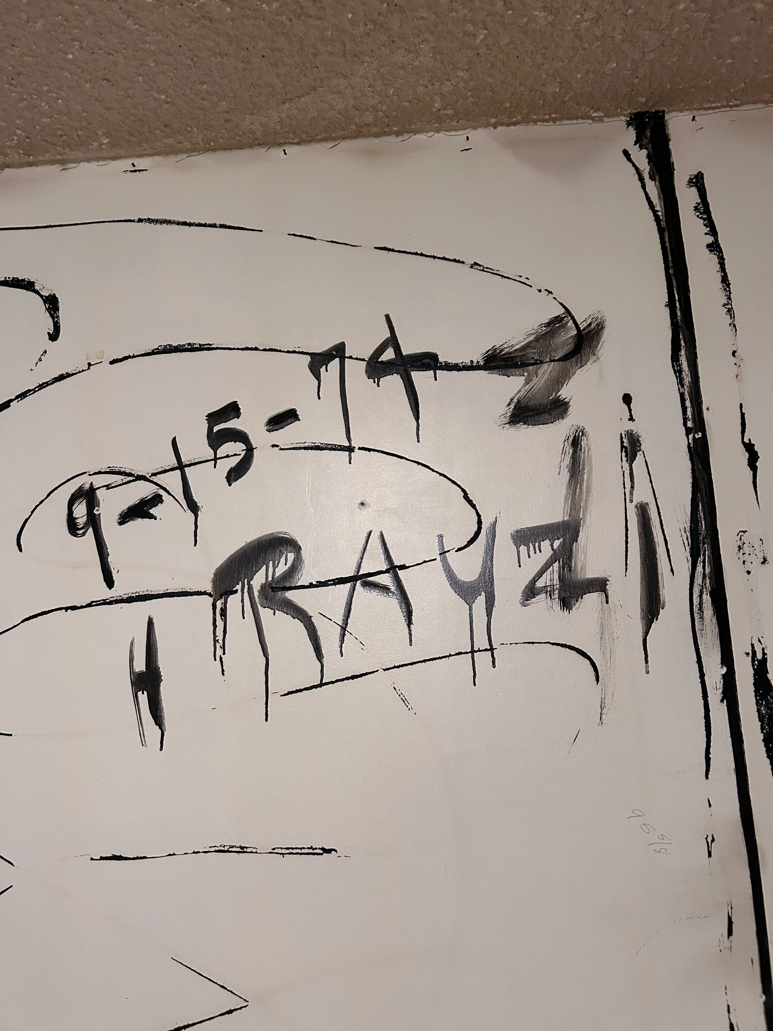 Close-up of a white wall with black glue which was used to write 9-15-74 and "Rauzi".