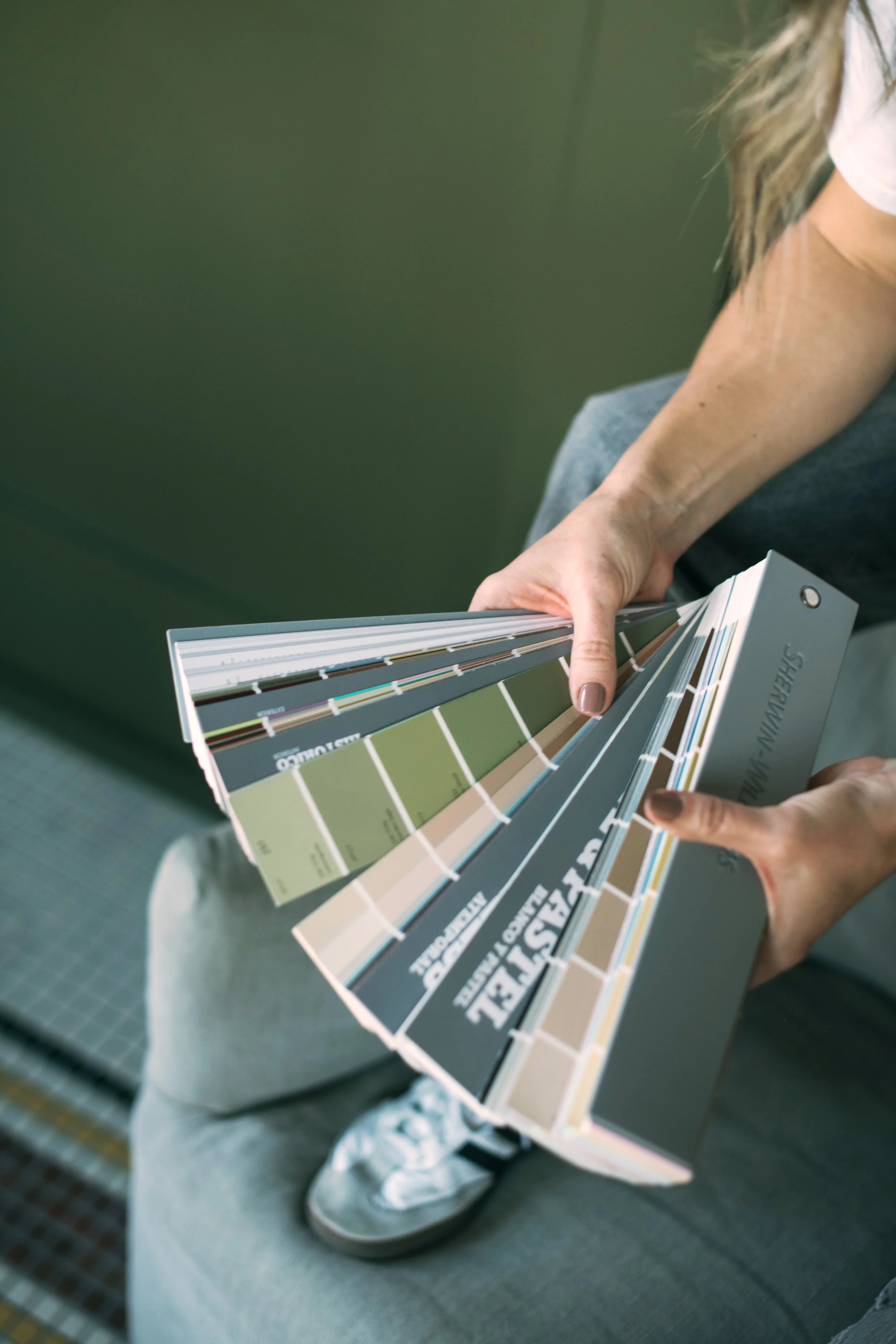 A person holding a color swatch palette with various paint color samples.