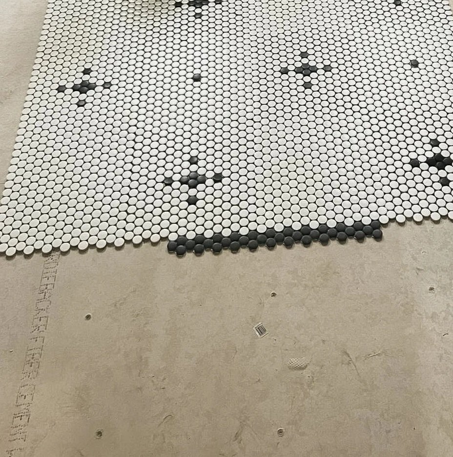 A mosaic of small black and white penny tiles arranged to reflect a snowflake.