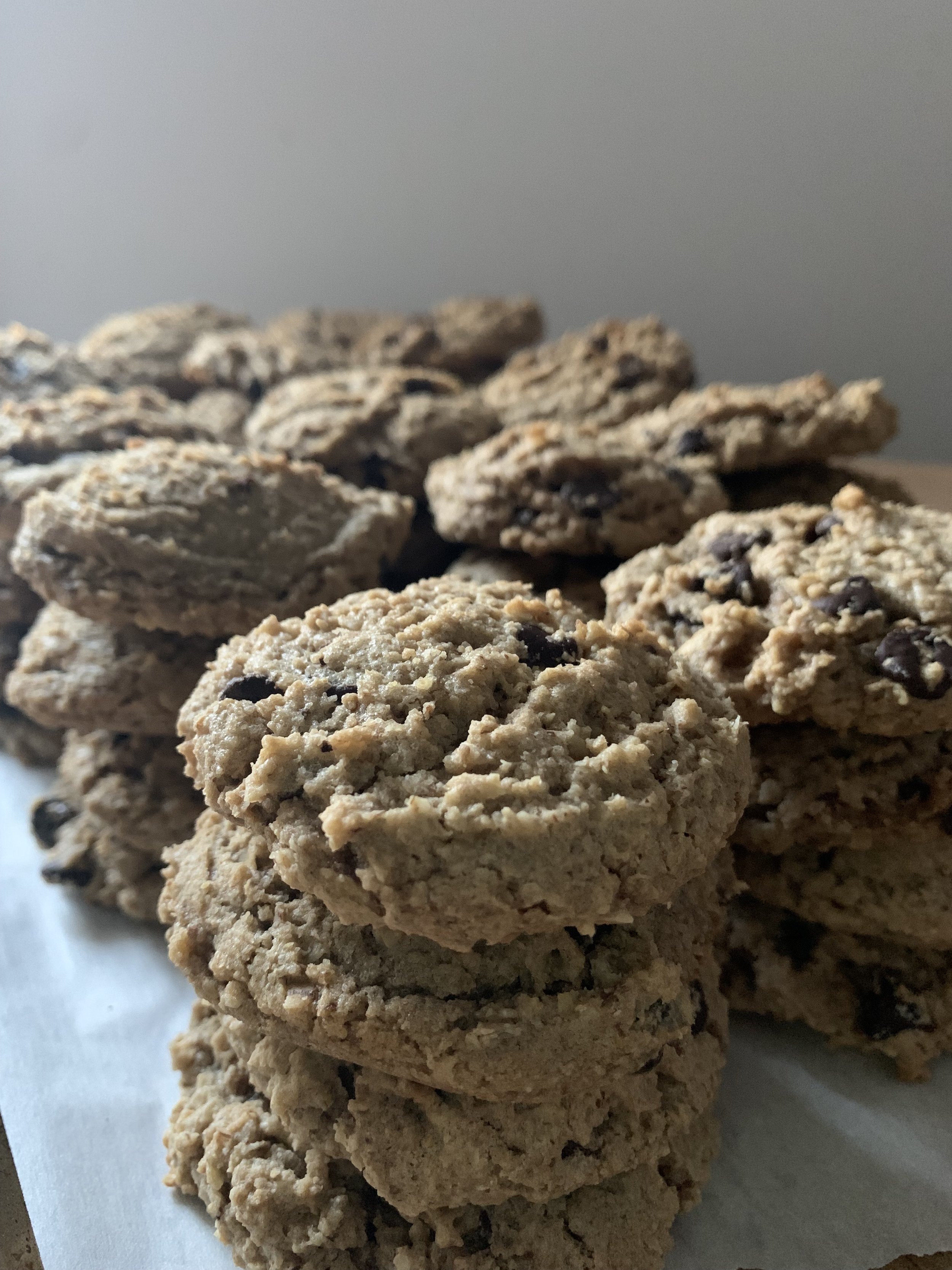 Close-up of a stack of chewy oatmeal cookies with chocolate chips on parchment paper.
