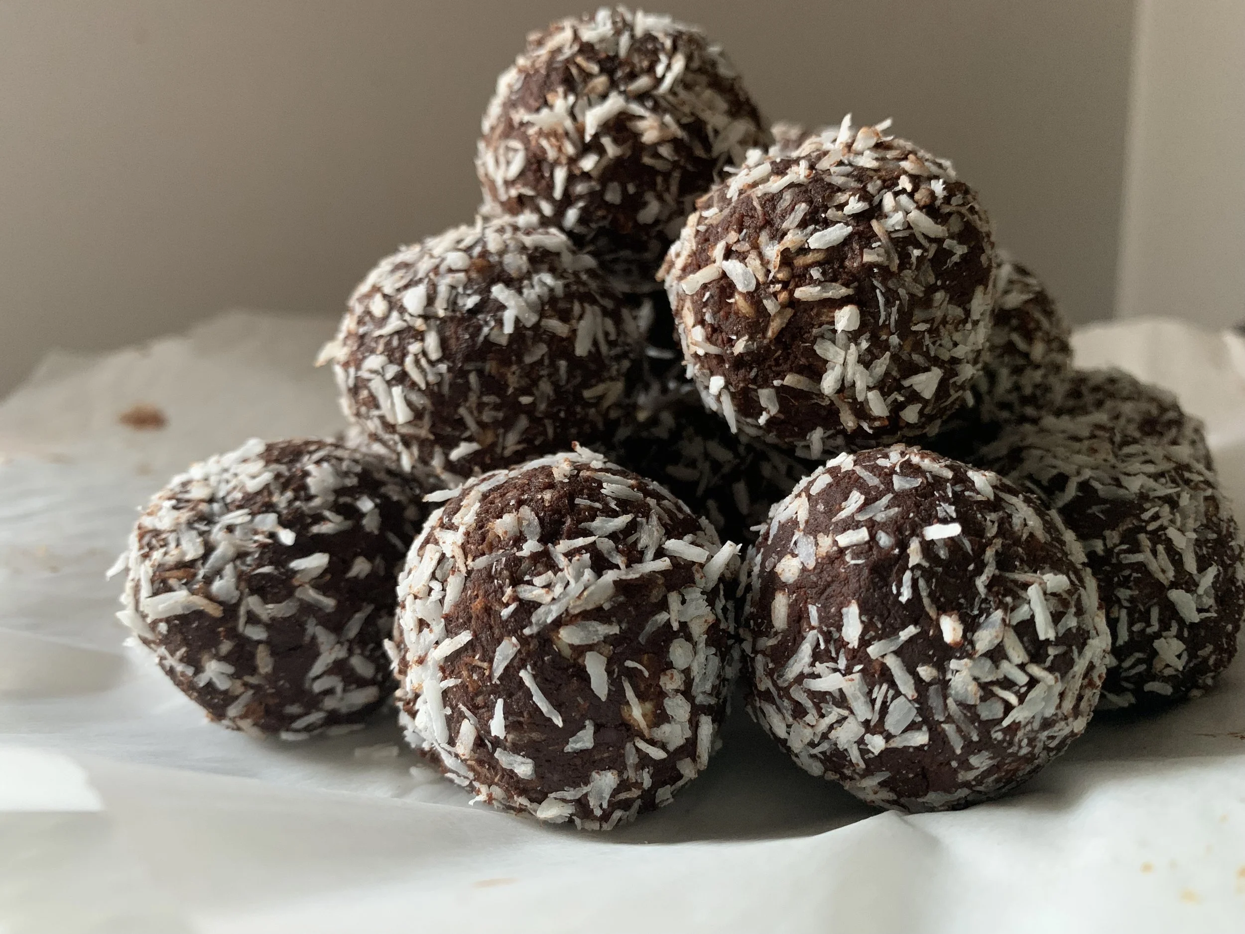 A pyramid of chocolate truffles coated in shredded coconut on white parchment paper.