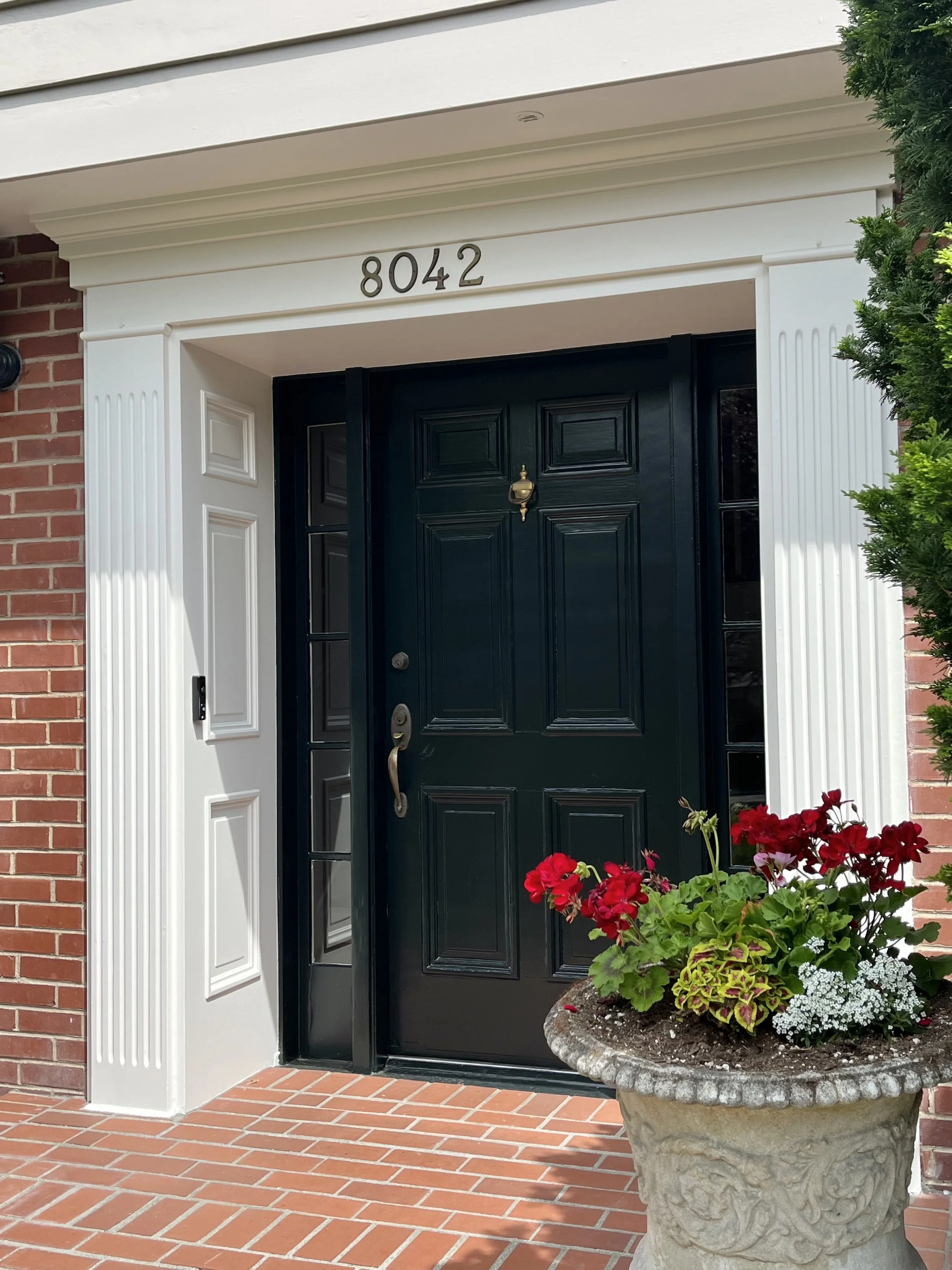 Bold black front door with white trim and brick siding.