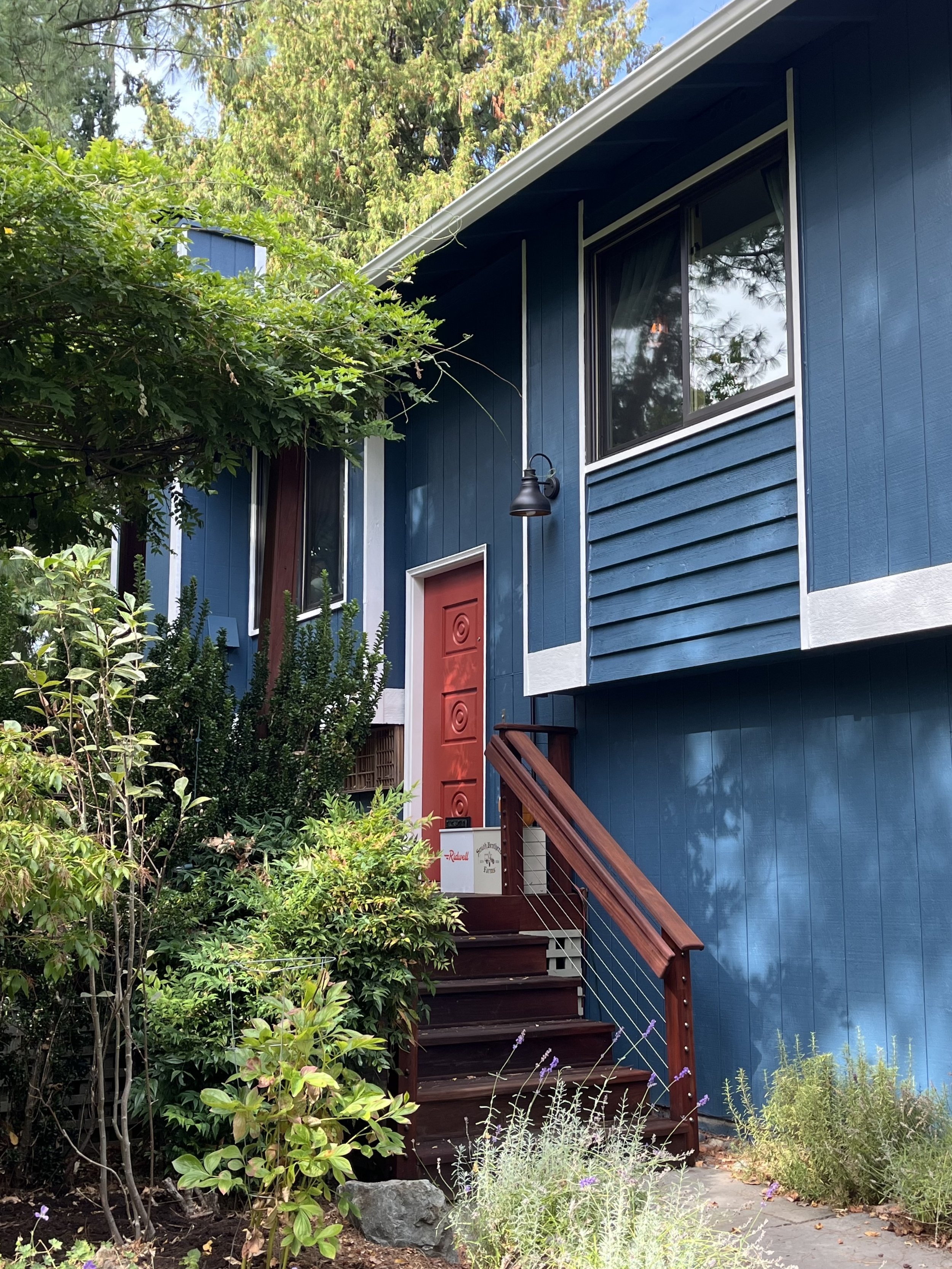 a home with rich and warm navy blue siding and a punchy red front door 