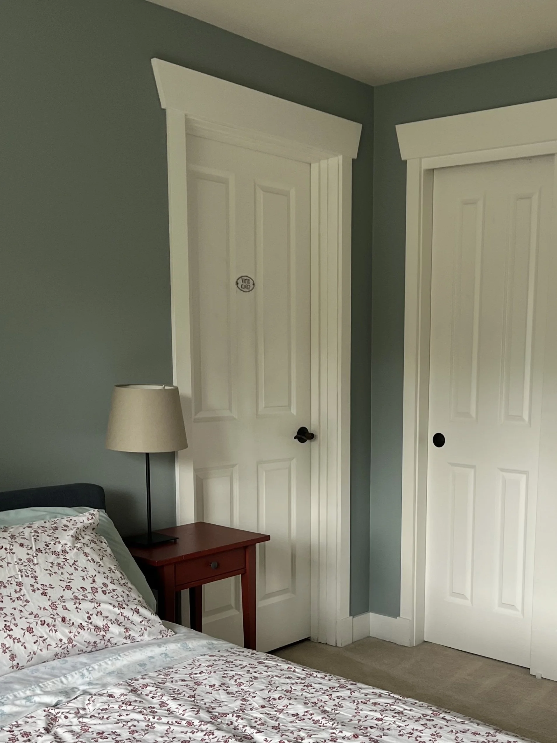 soft and airy blue guest bedroom paint color with red floral sheets and creamy white trim and doors