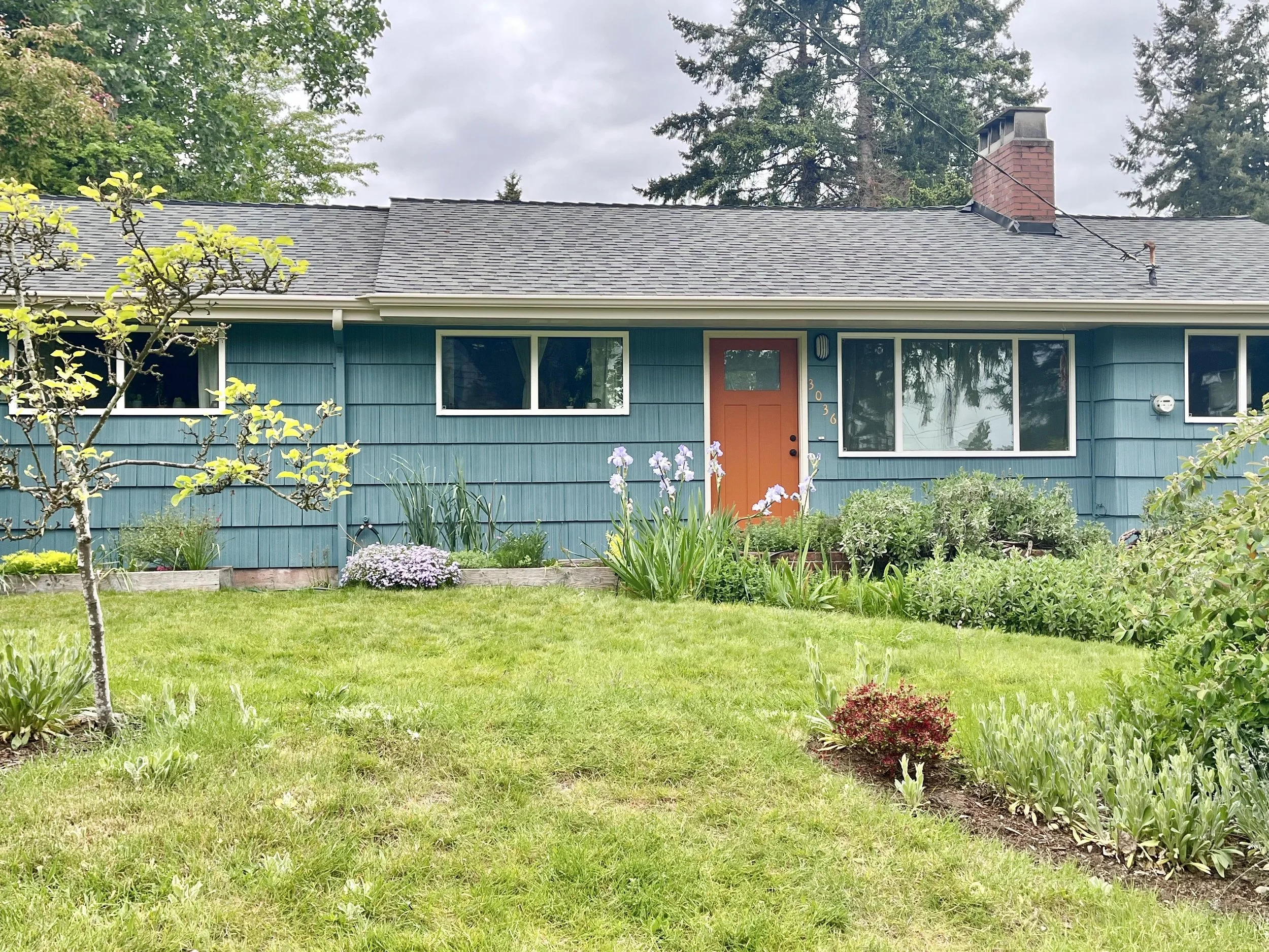 Teal ranch house with creamy trim and an orange front door