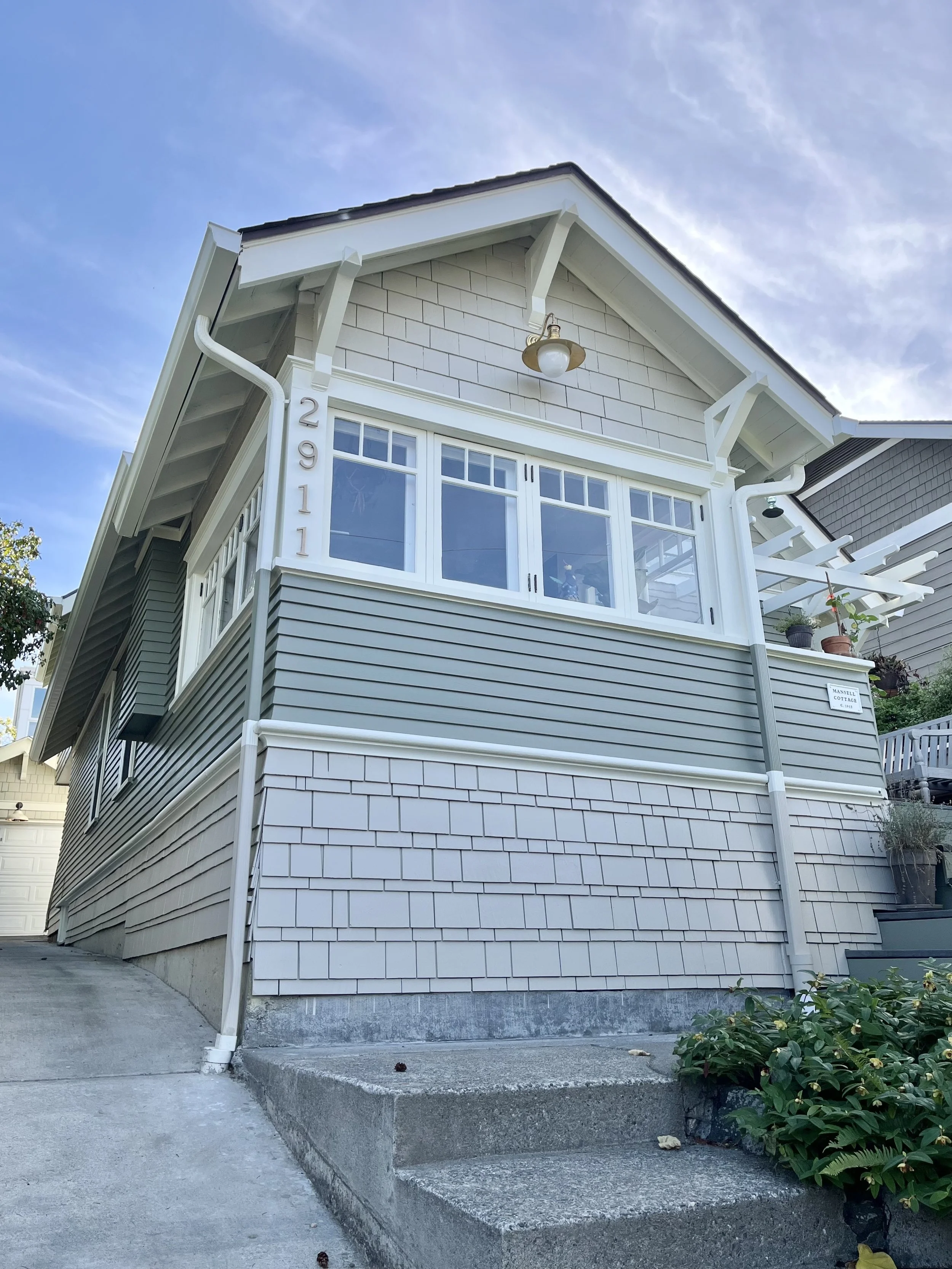 soft greige shingle siding, gray green lap siding, and creamy white trim refresh this coastal home's exterior