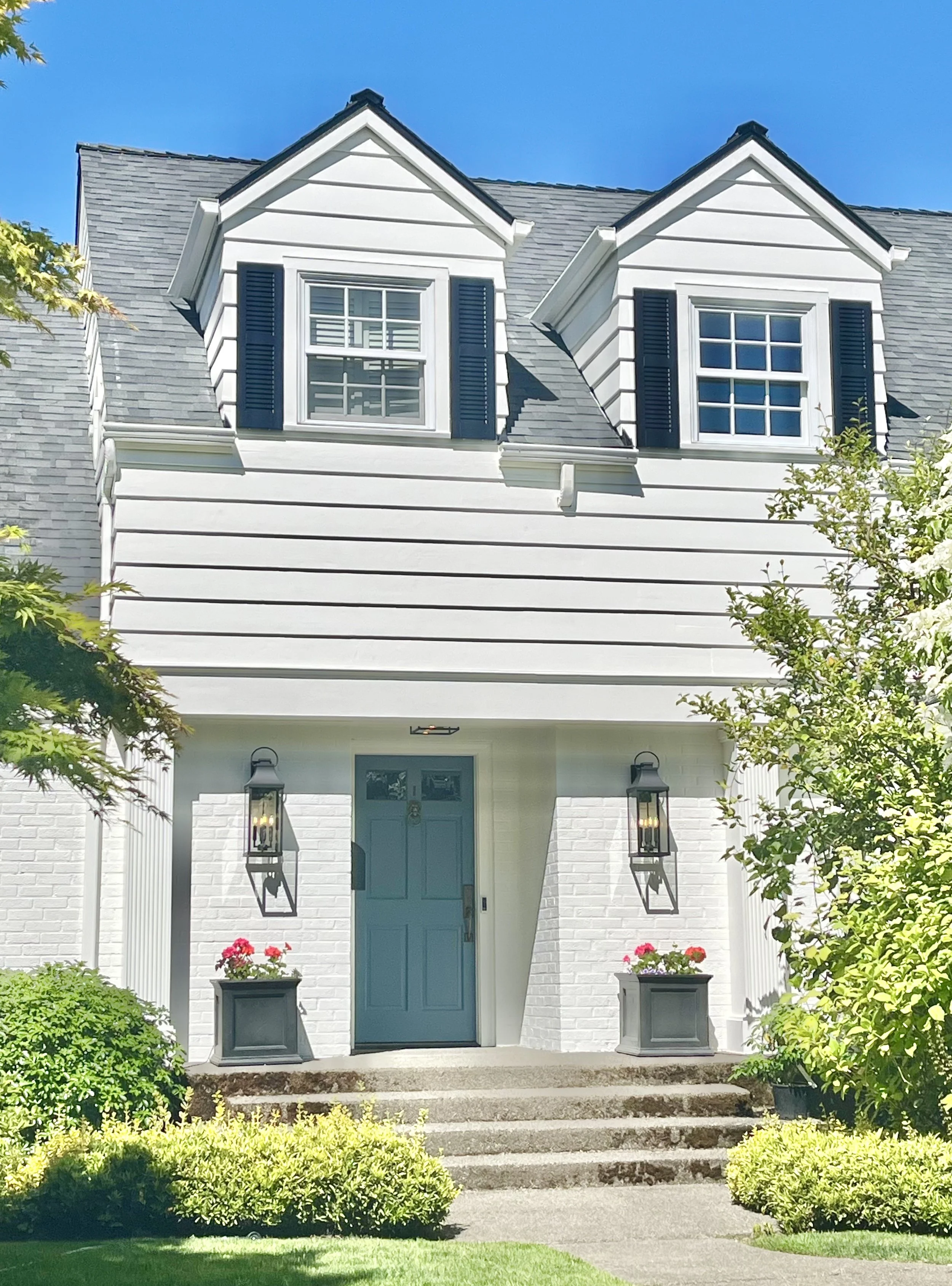 bright and cheerful white cape cod style home with a pleasant blue front door