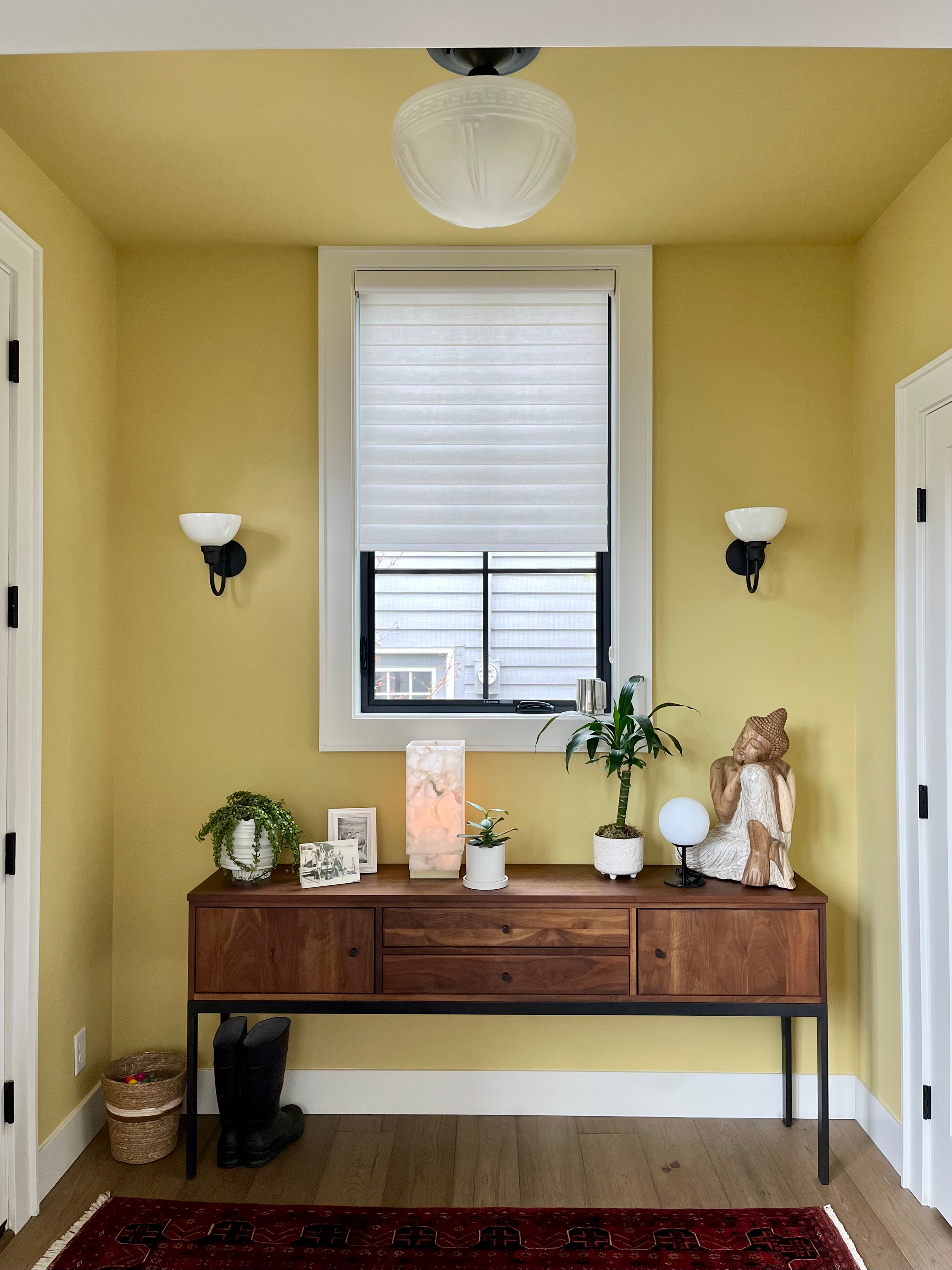 Straight on view of a warm walnut wood console, adorned with various plants and decor. The walls and ceiling are color-drenched in the color Mother Earth, an energizing and spunky chartreuse.