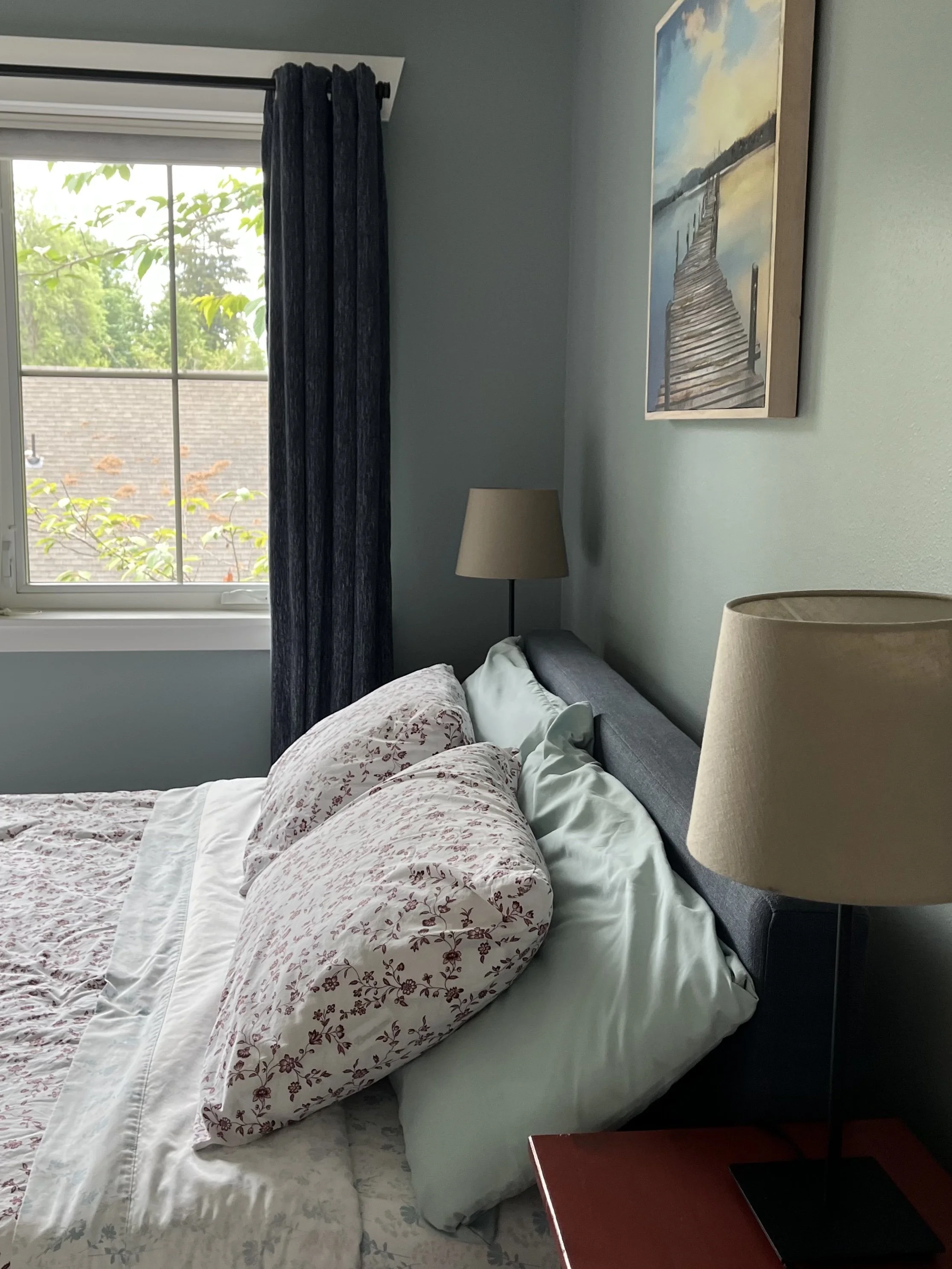 soft and airy blue guest bedroom paint color with red floral sheets and navy draperies