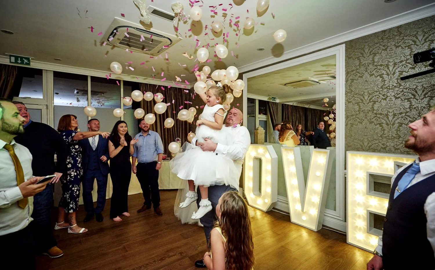 The groom picks up his little daughter to dance with her at the reception.