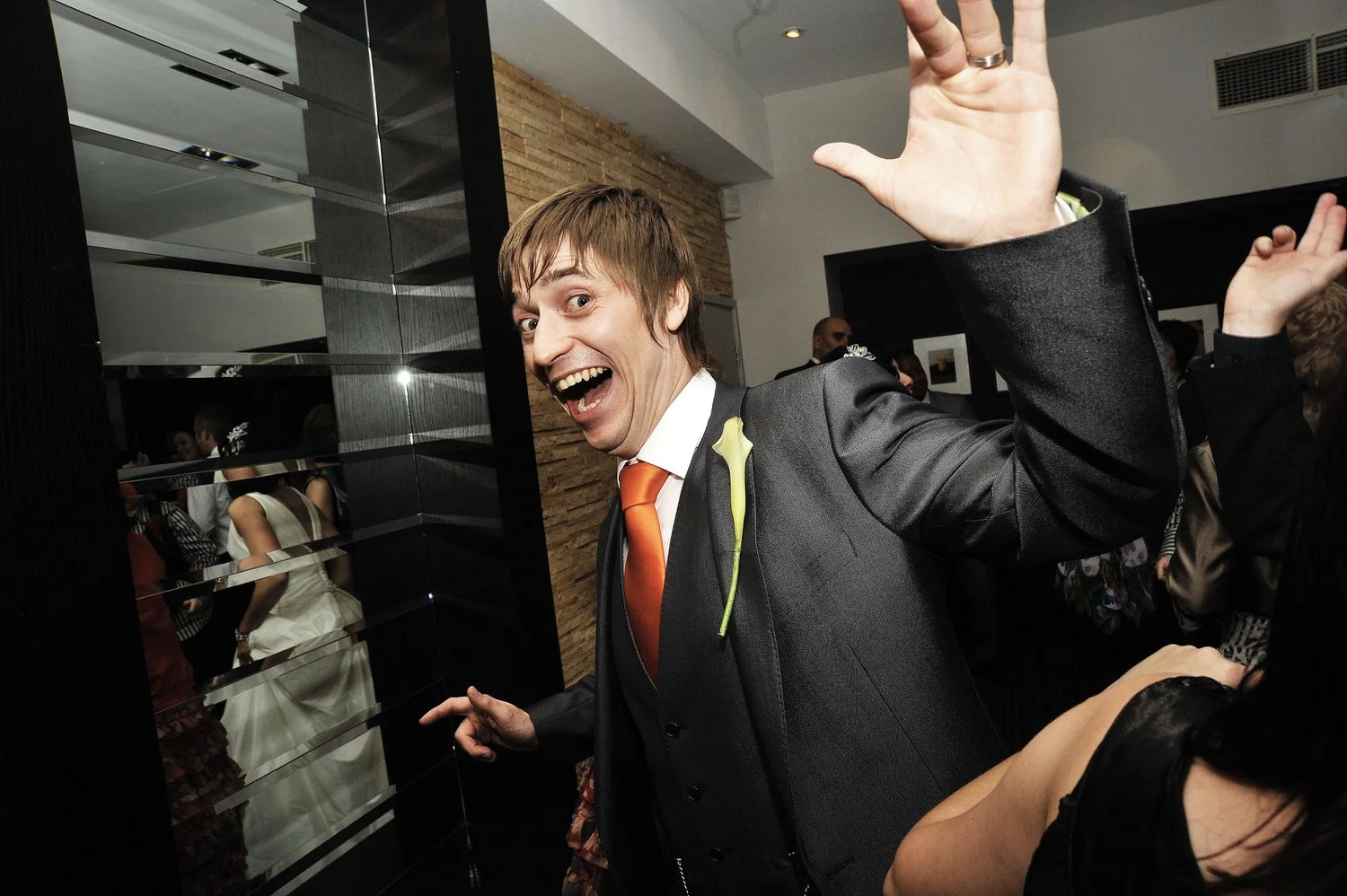 Groom stands with huge grin holding hands in the air.