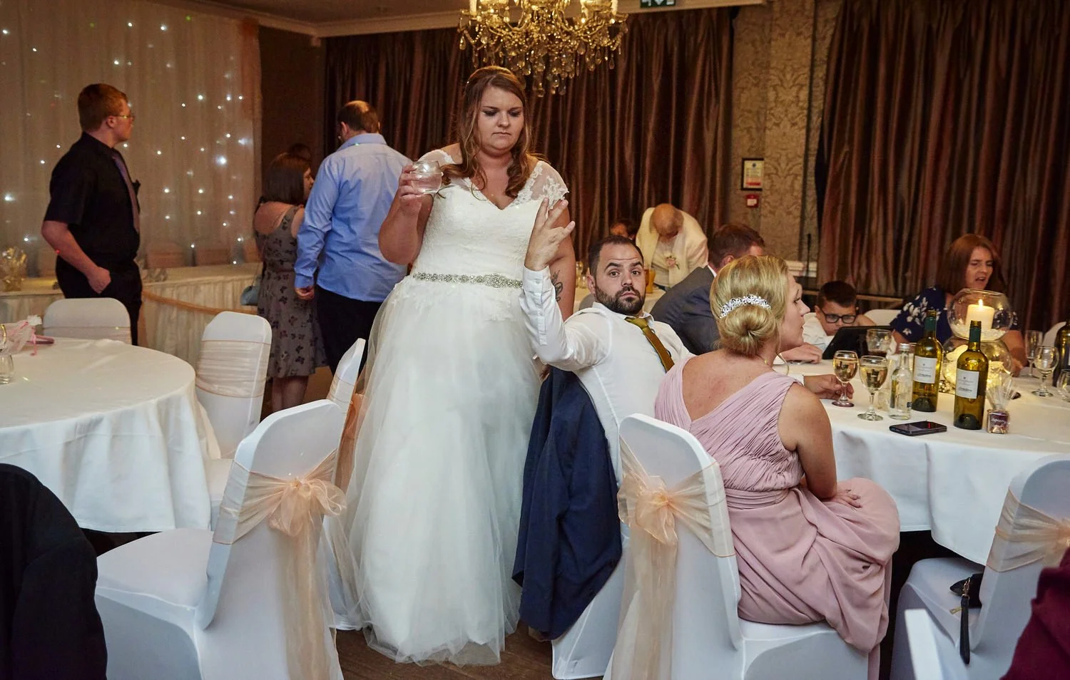 The bride moves through the room as her guests eat.