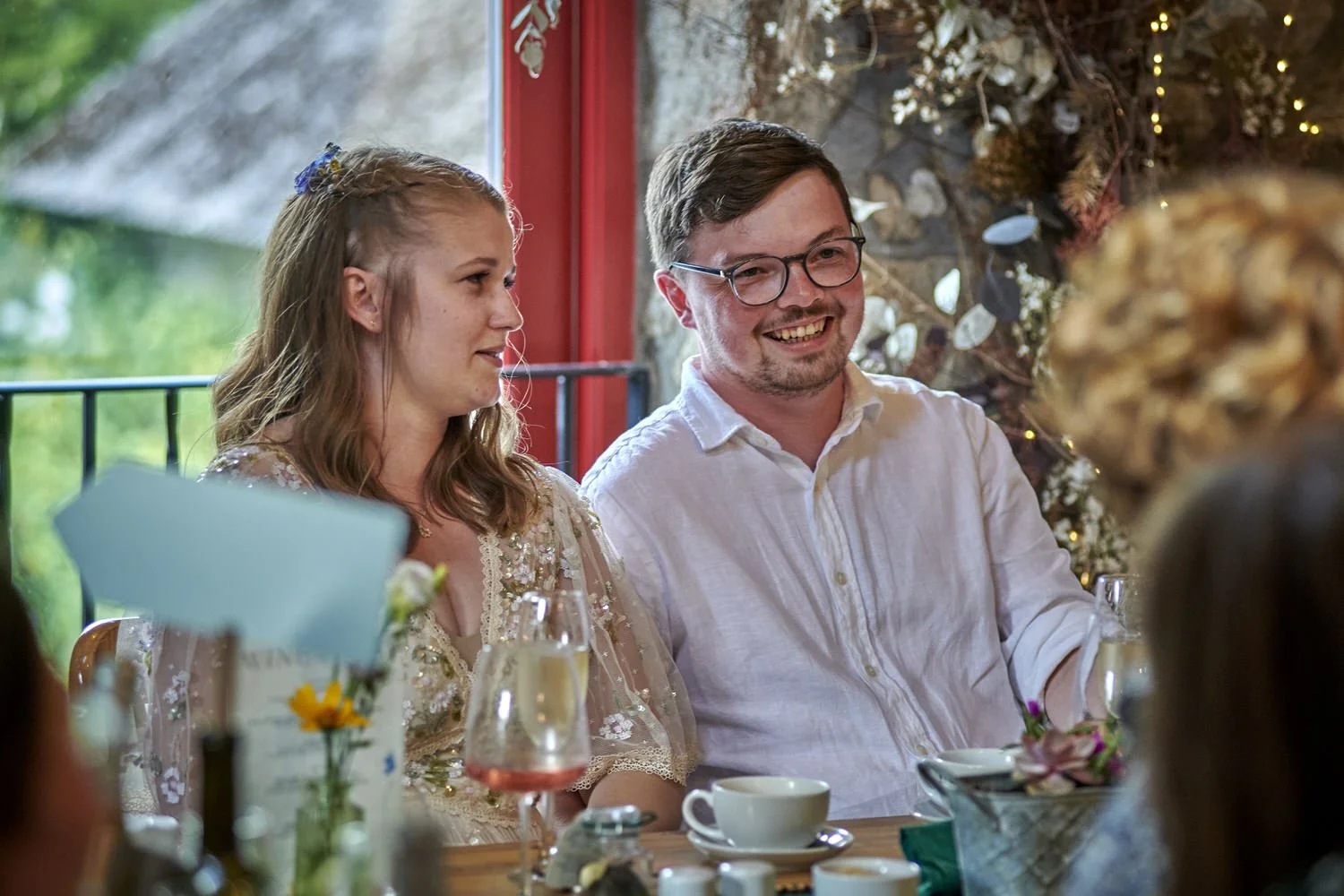 Bride and groom sit together at the top table listening to speeches.