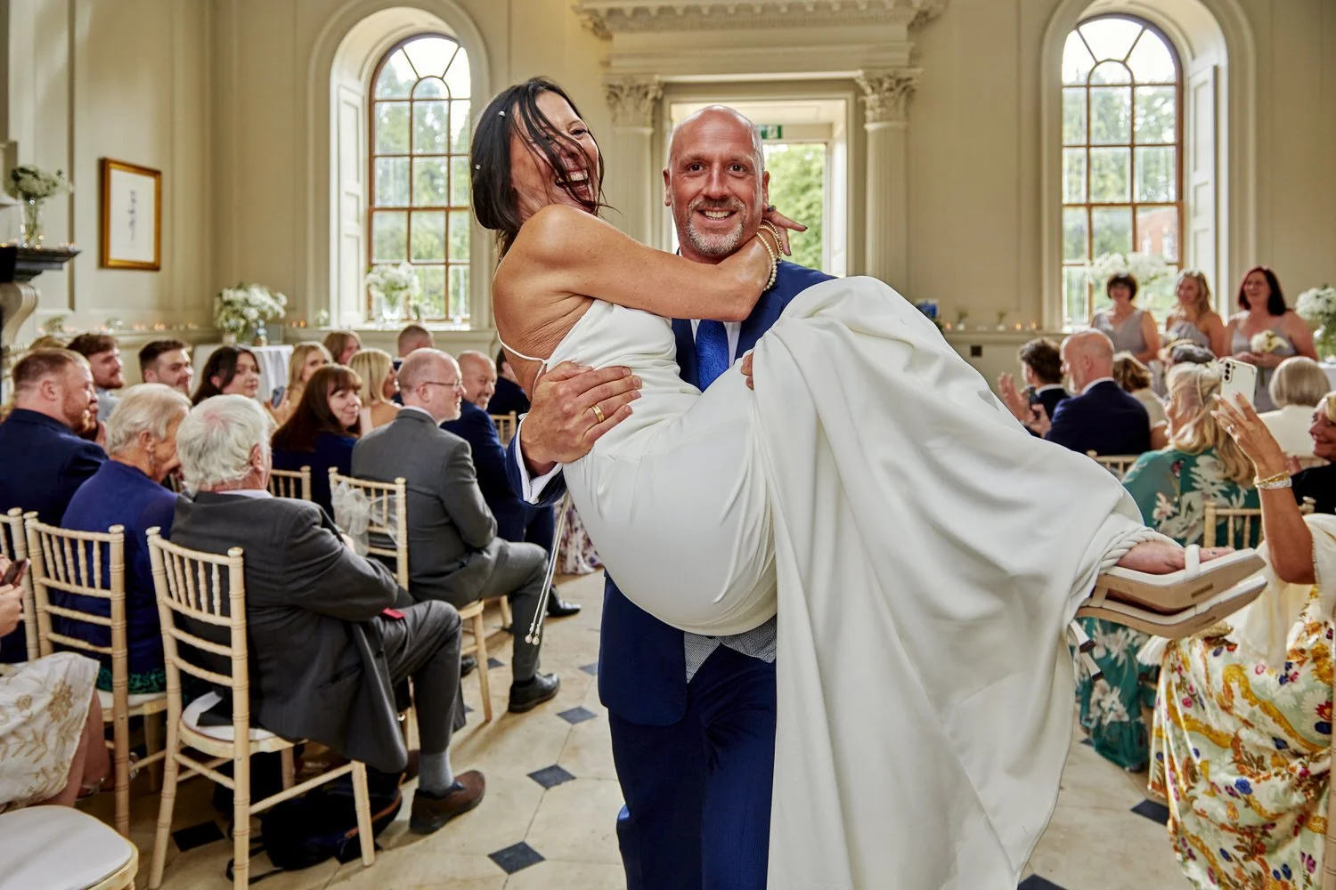 Close-up view as groom carries his new wife in his arms as they leave the ceremony.