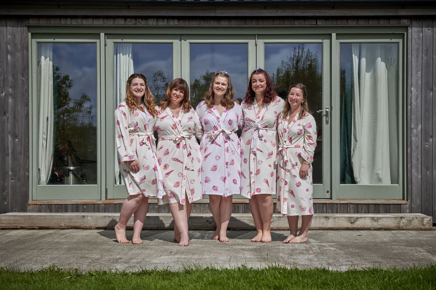Mother of bride and bridesmaids line up outside in matching robes before dressing for the wedding.