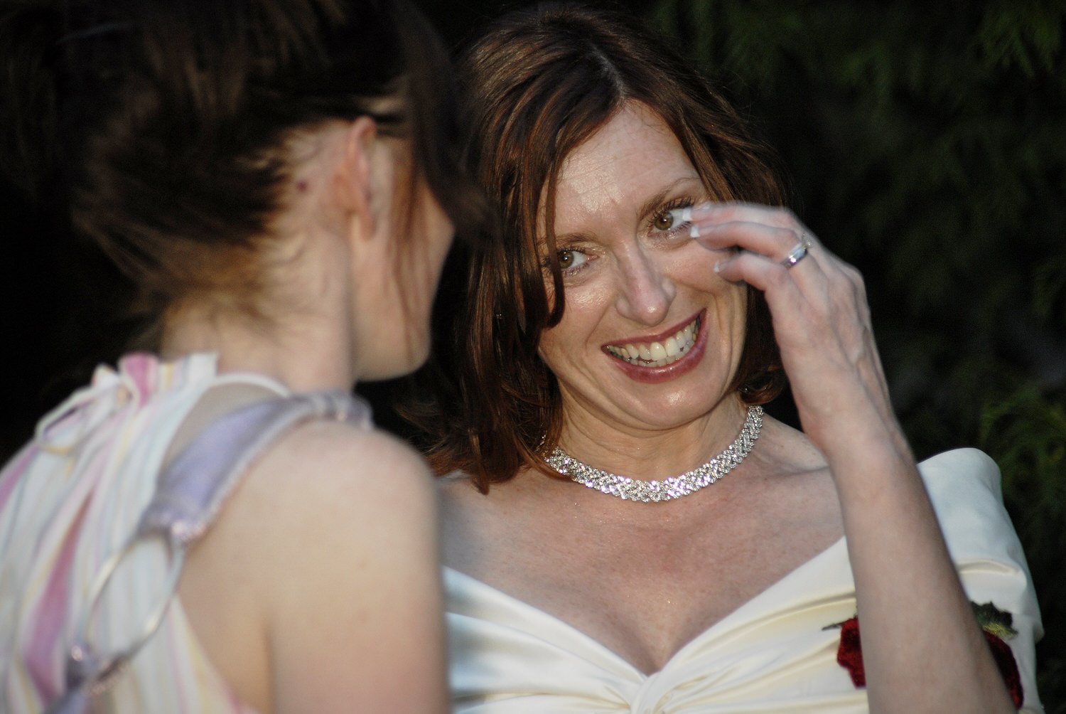 Bride cries happy tears while talking to a wedding guest.