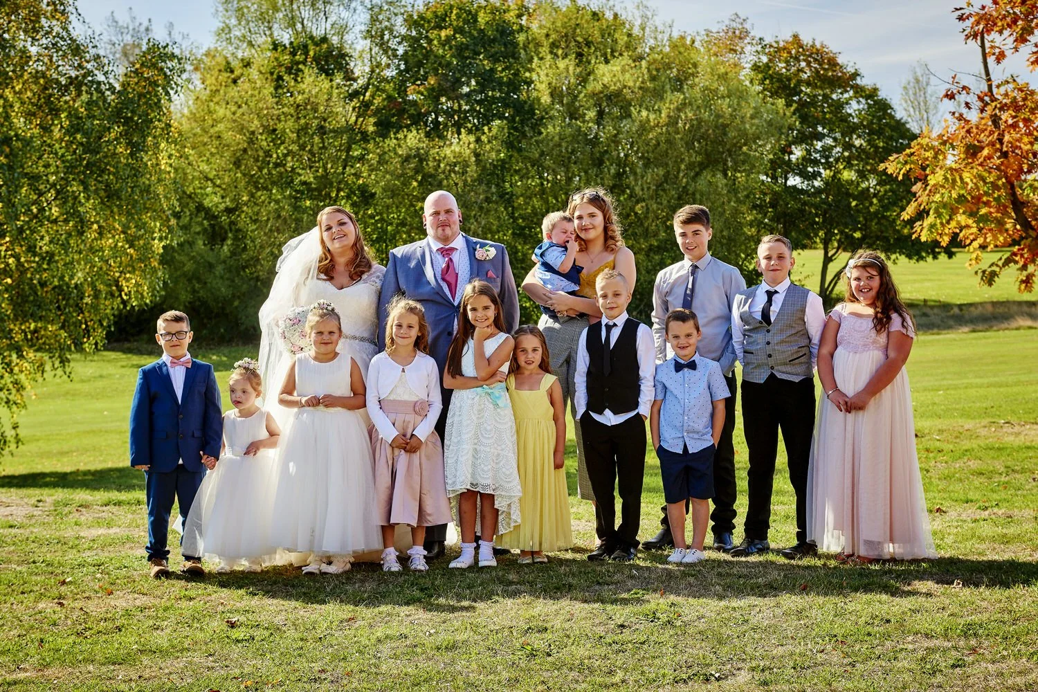 A large bridal party group and friends pose for an official photograph.