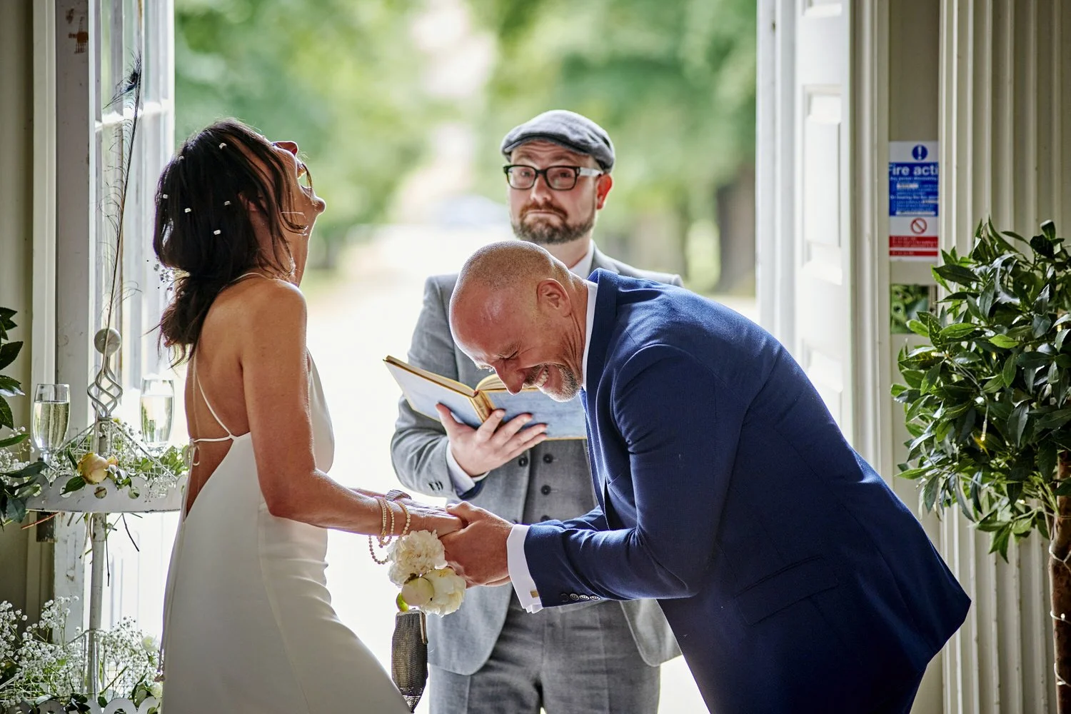 Bride and groom laugh and throw their heads back as they are married.