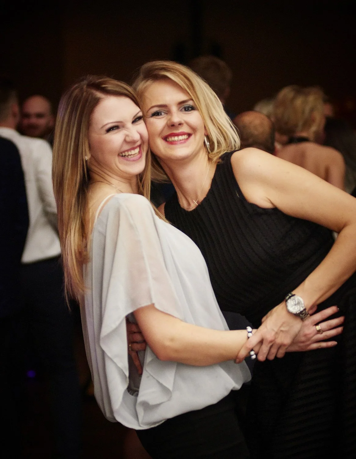 Two friends hug and smile at the camera.