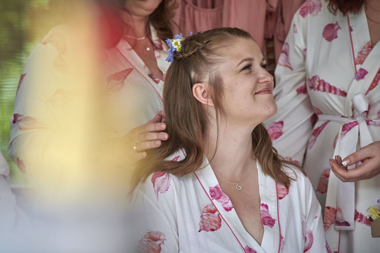 Bride looks up and smiles with out-of-focus bridesmaids surrounding her.