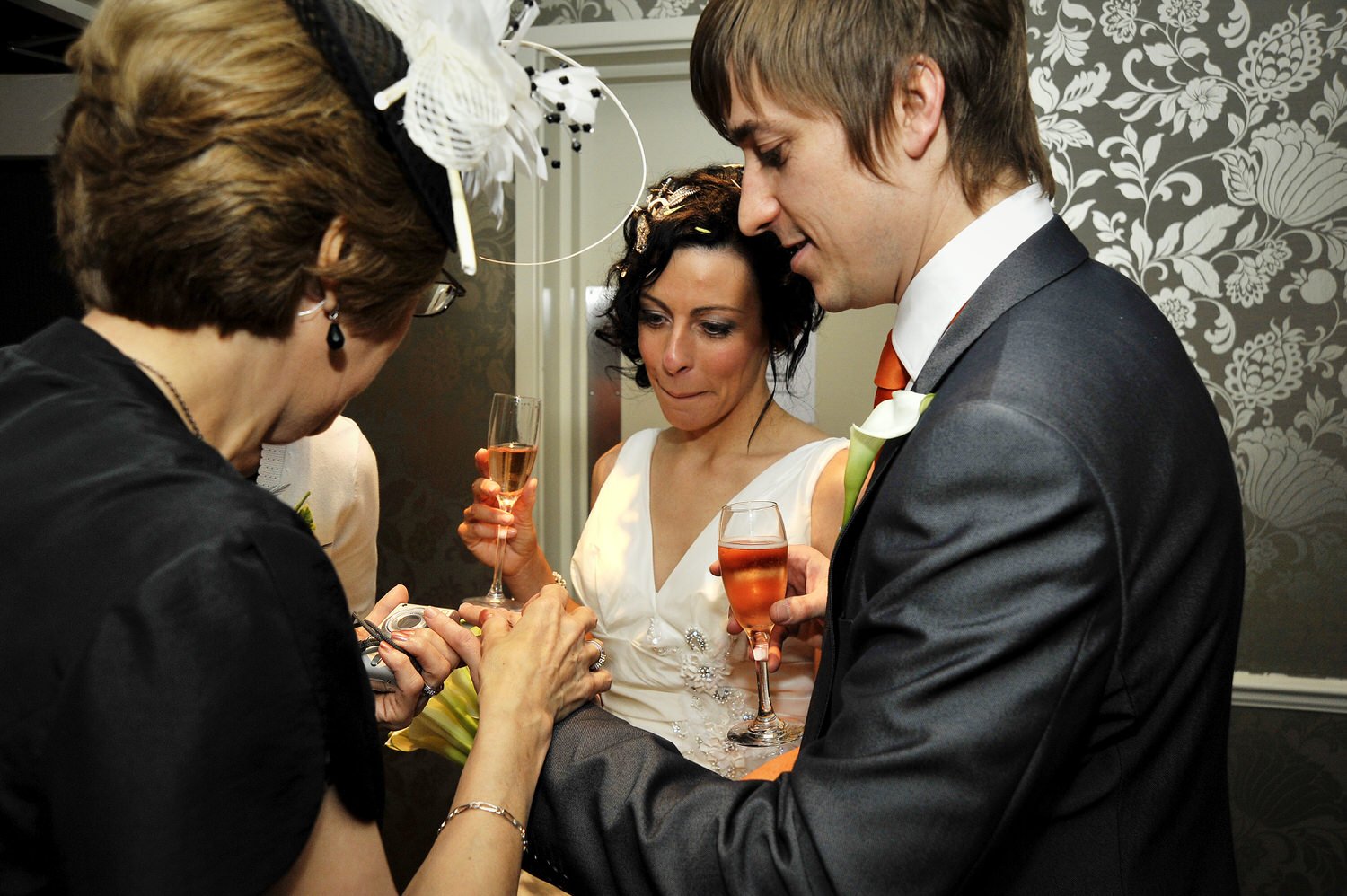 Bride and groom greet guests with drinks in their hands.
