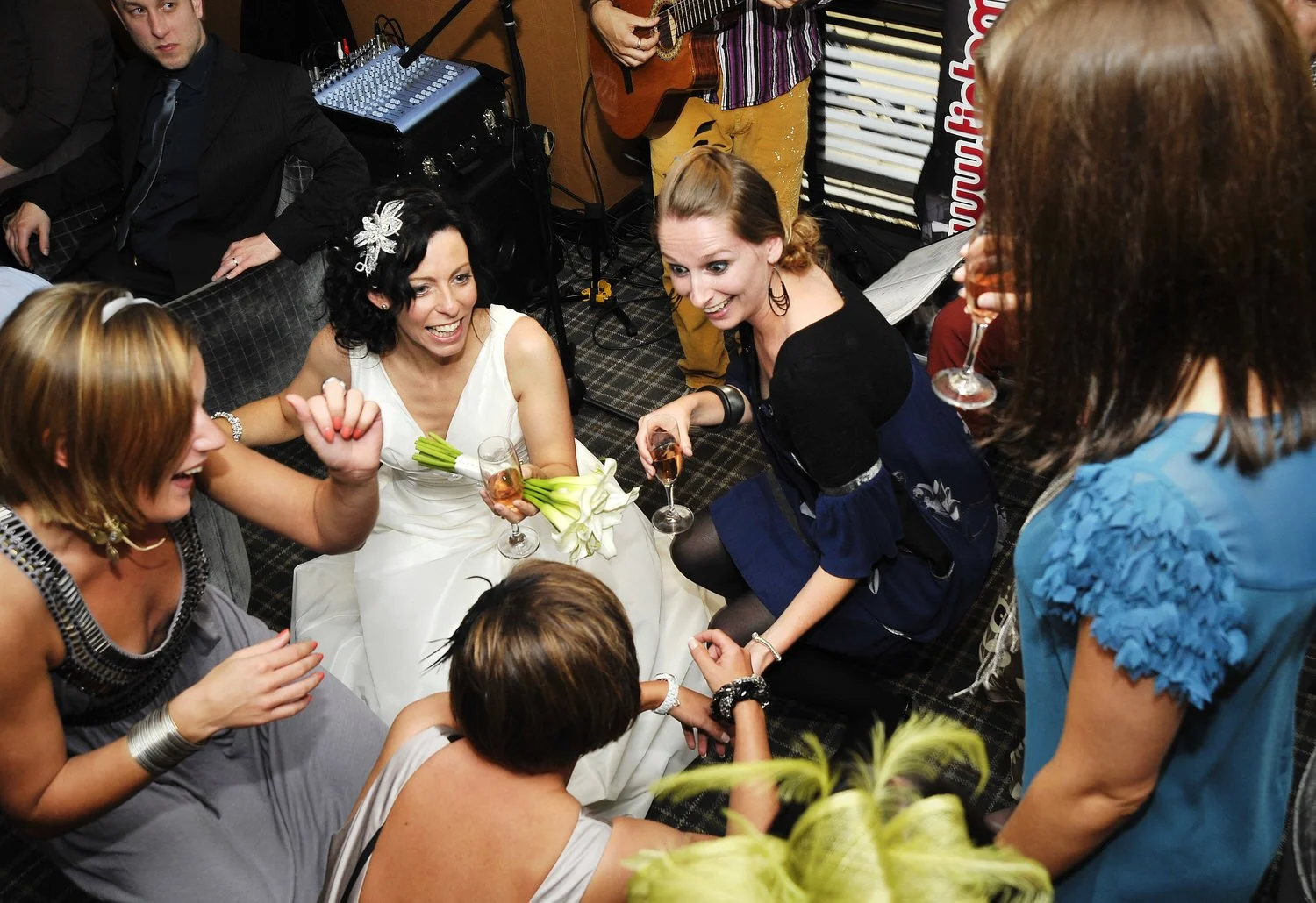 Bride sits on the floor surrounded by friends smiling.