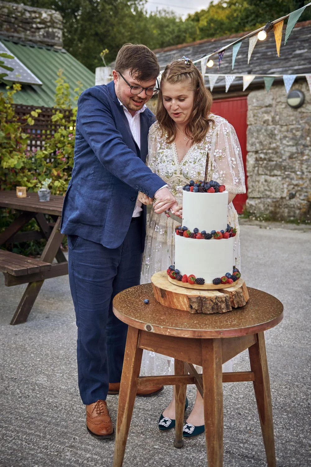 Bride and groom cut the wedding cake in a courtyard.