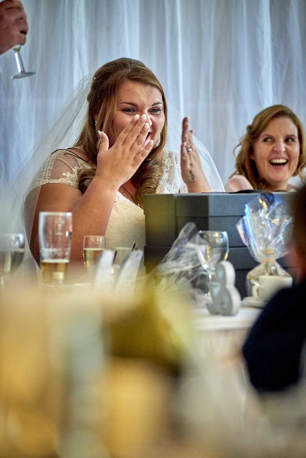 The bride holds her hands to her face as she mops at happy tears.