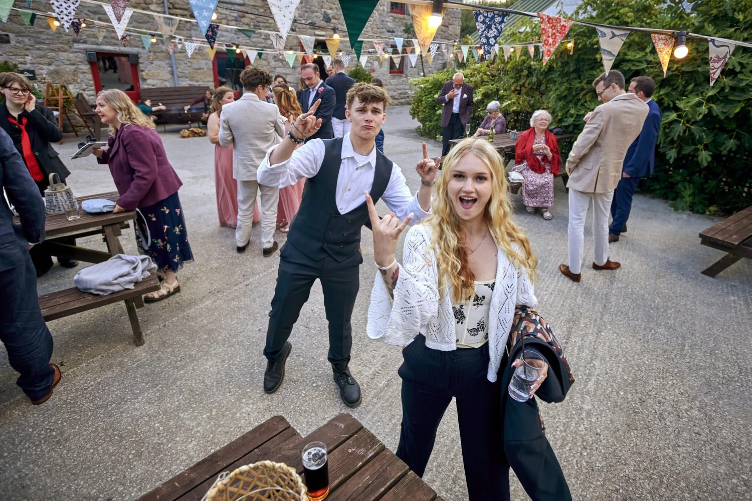 Two guests pose among other guests dancing.