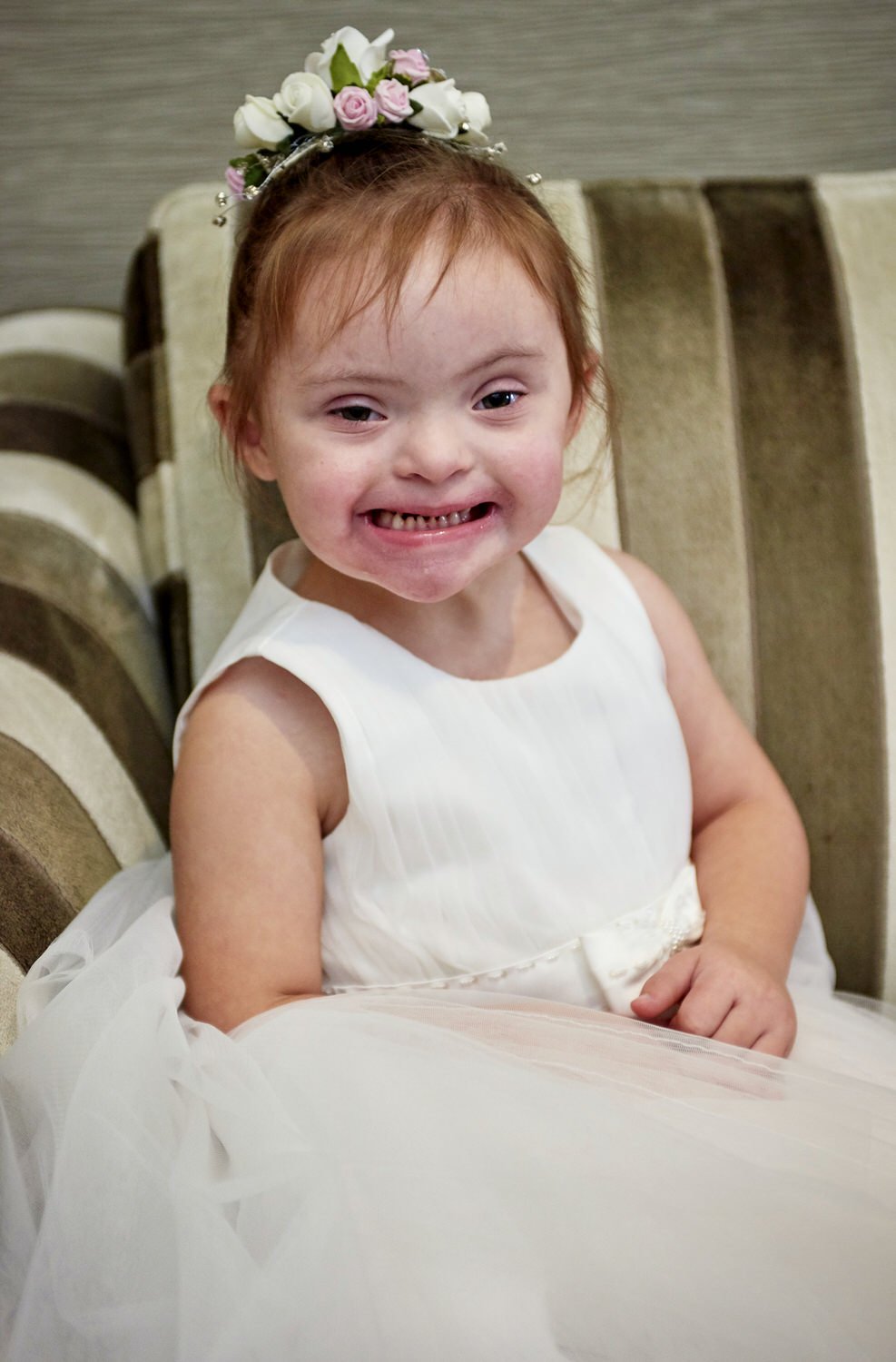 A young bridesmaid smiles at the camera, waiting for the party to begin.