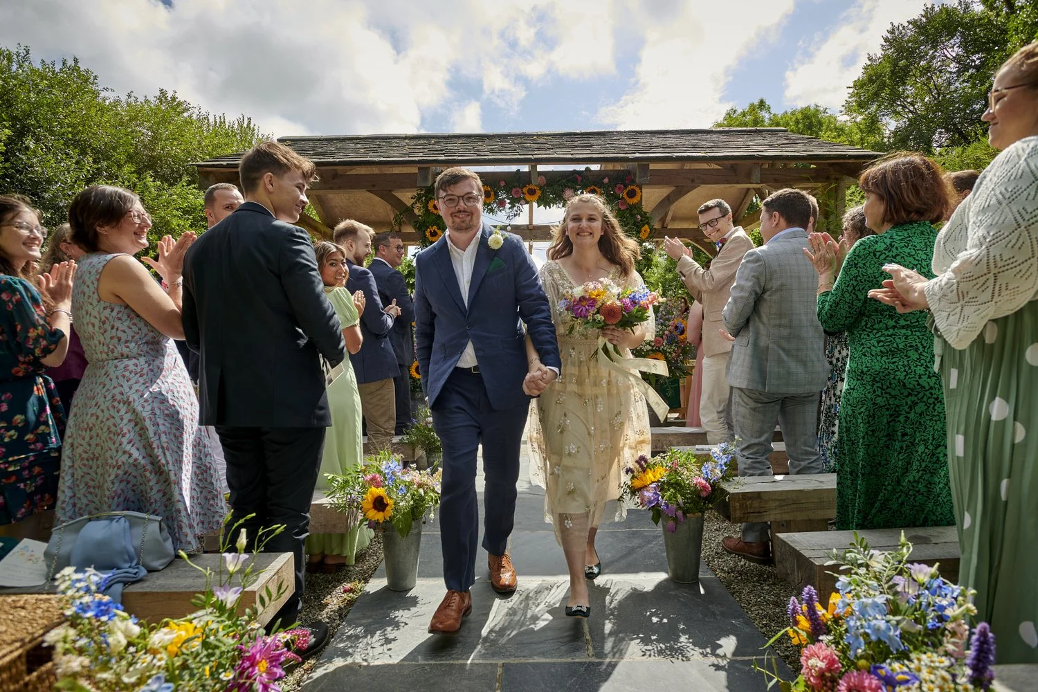Close up view of bride and groom walking back down the aisle together as guests look at them and clap.