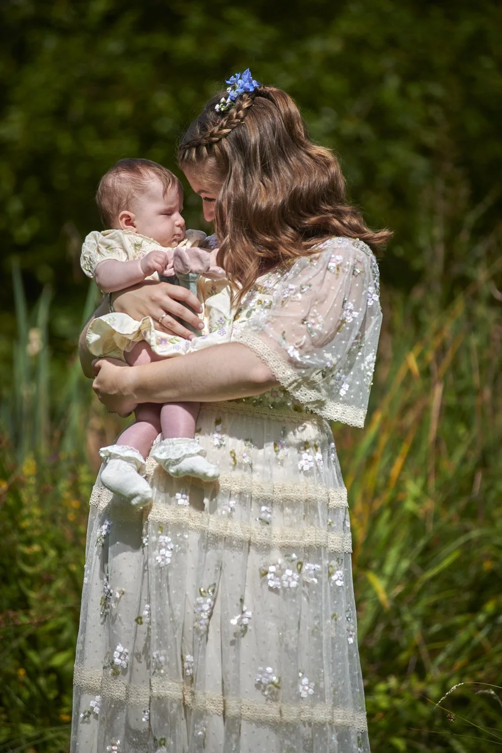 Bride looking at her friend's baby while holding her in her arms.