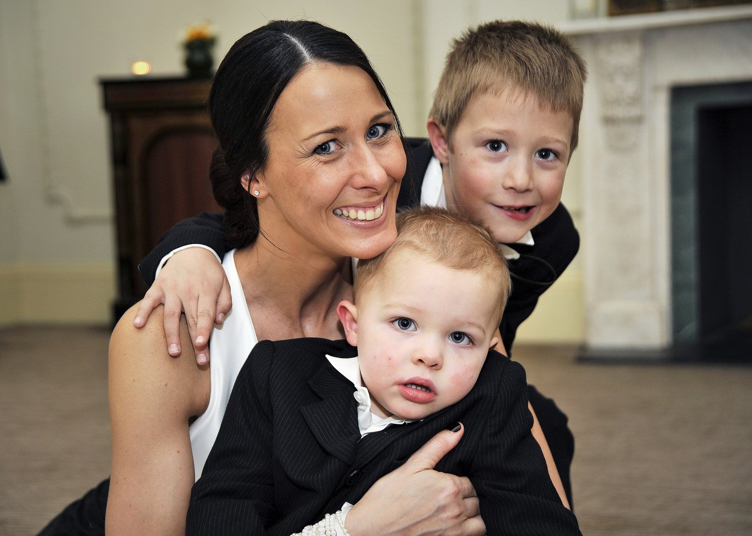 ride poses sat on the floor with her two children smiling at the camera.
