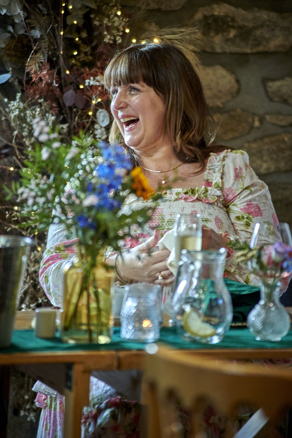 Mother of the bride laughs and smiles as she looks across to her daughter.