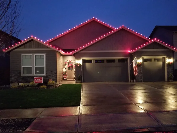 Single-story home with red and white Christmas lights along the roof peaks