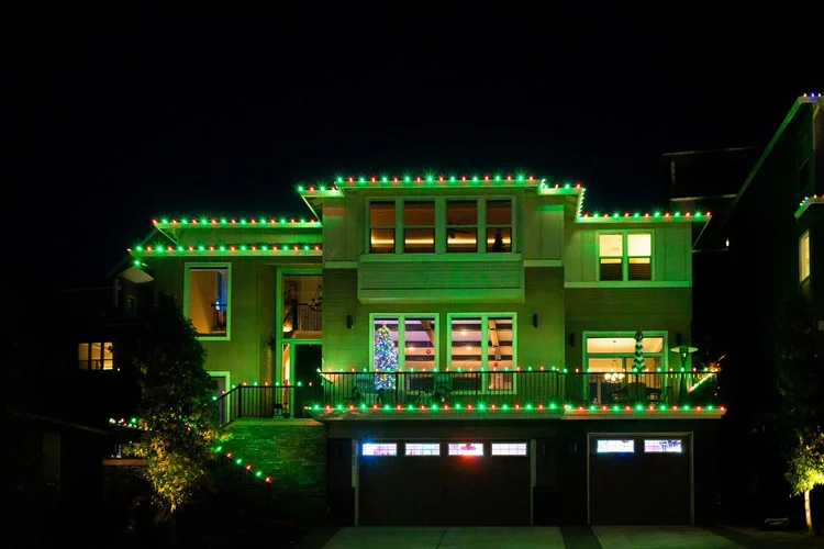 Green and white Christmas lights on a large two-story home