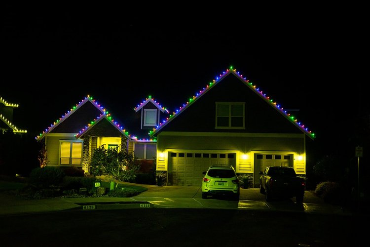 Multicolor C9 lights along the rooflines of a home with a lit front porch