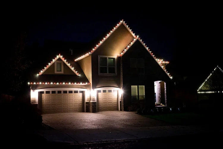 Warm white lights tracing the gables of a two-story home at night