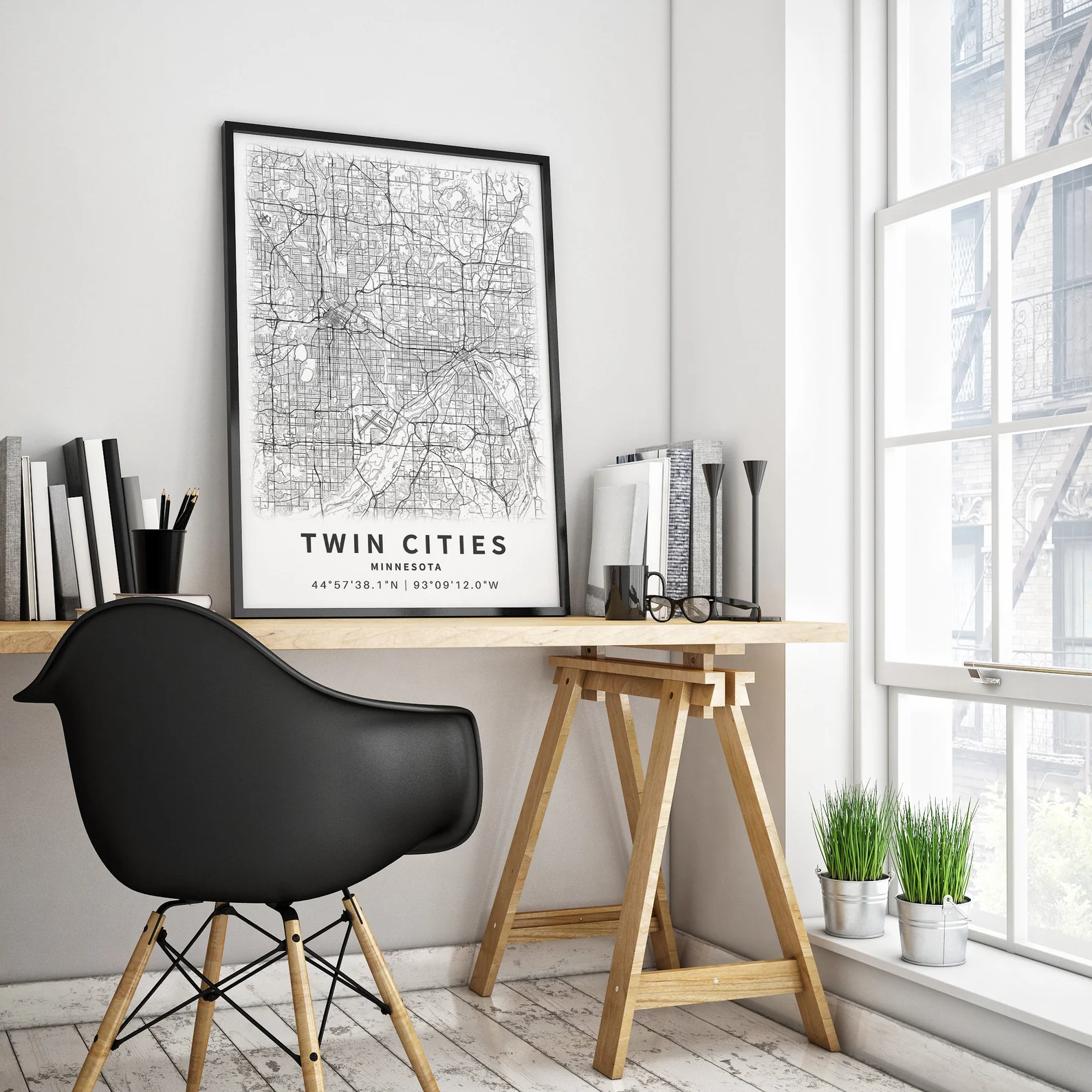 A modern home office with a black chair, a light wood desk, a framed map of Twin Cities, Minnesota, on the desk, and potted plants by a large window.