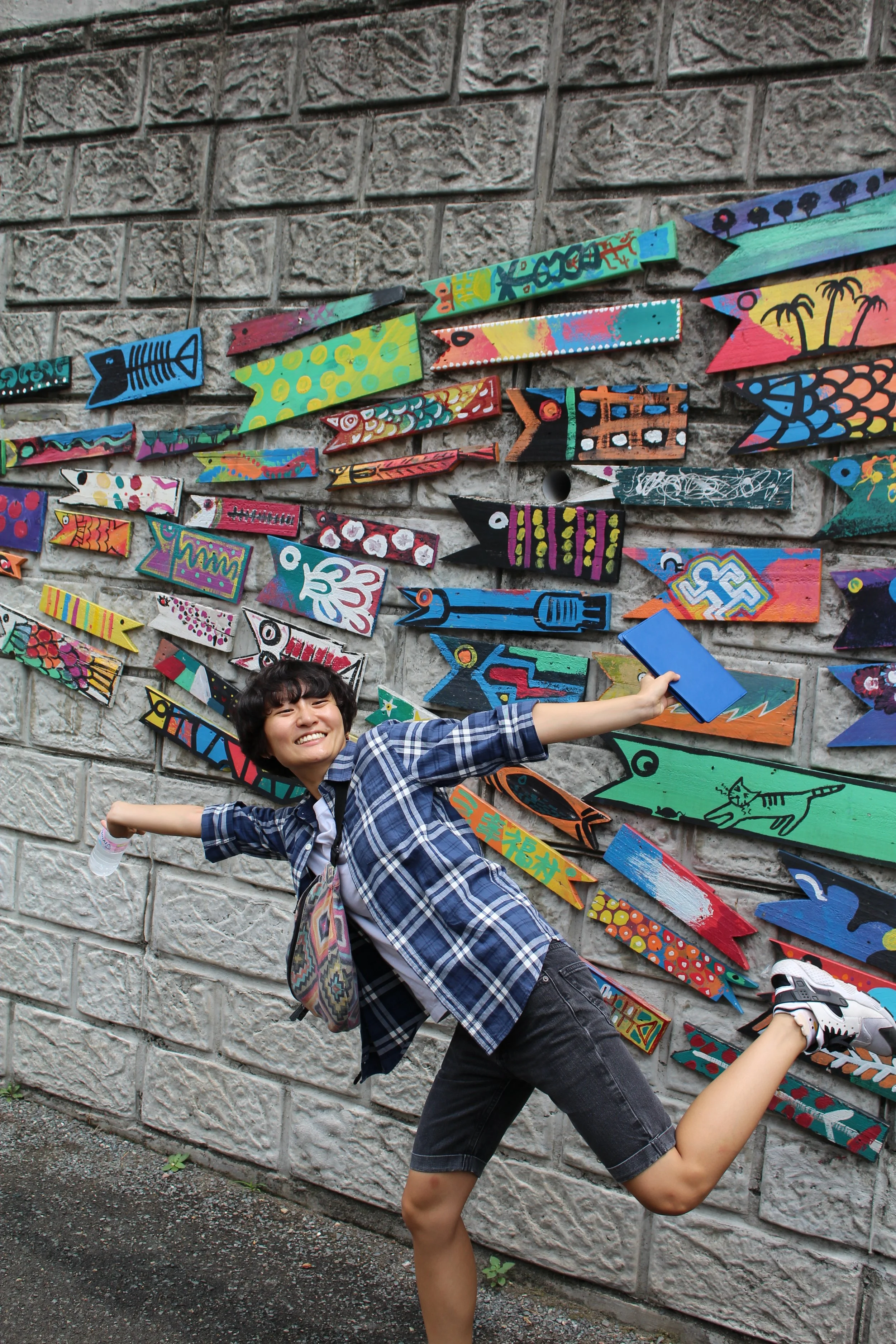 KASC delegate playfully posing in front of a colorful wall mural in Busan, South Korea during a cultural activity, representing student-led U.S.–Korea exchange.