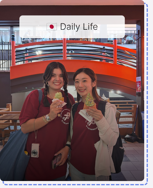 Two JASC delegates smile and pose with Japanese treats in a hallway, capturing everyday life and friendships during the Japan-America Student Conference.