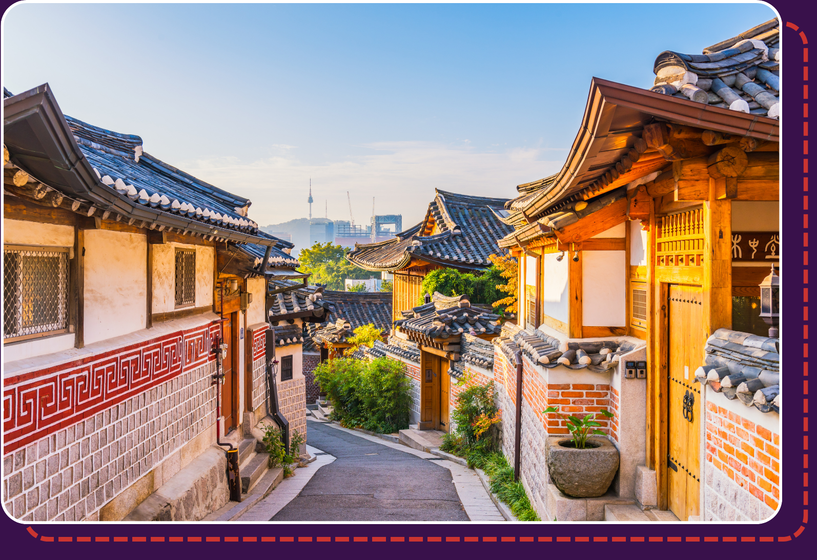 Traditional hanok rooftops line a quiet street in Bukchon Hanok Village, with Seoul Tower visible in the background at sunrise.