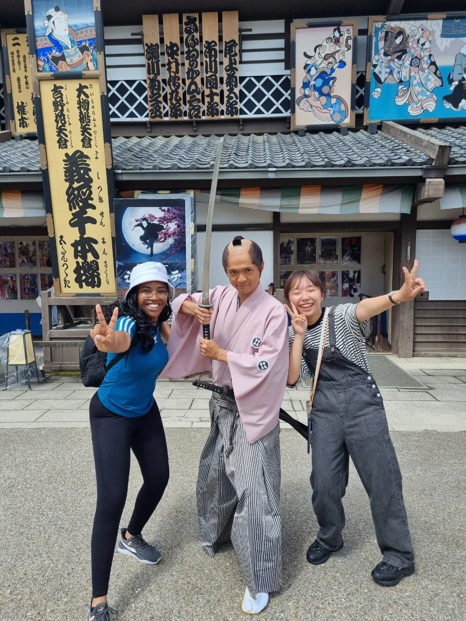 Two JASC delegates posing with a costumed samurai actor in Japan, capturing cultural immersion and people-to-people exchange in U.S.–Japan