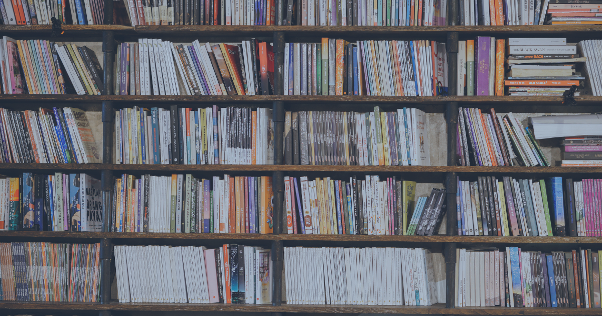 Shelves filled with a large collection of books in various colors and sizes, organized horizontally.