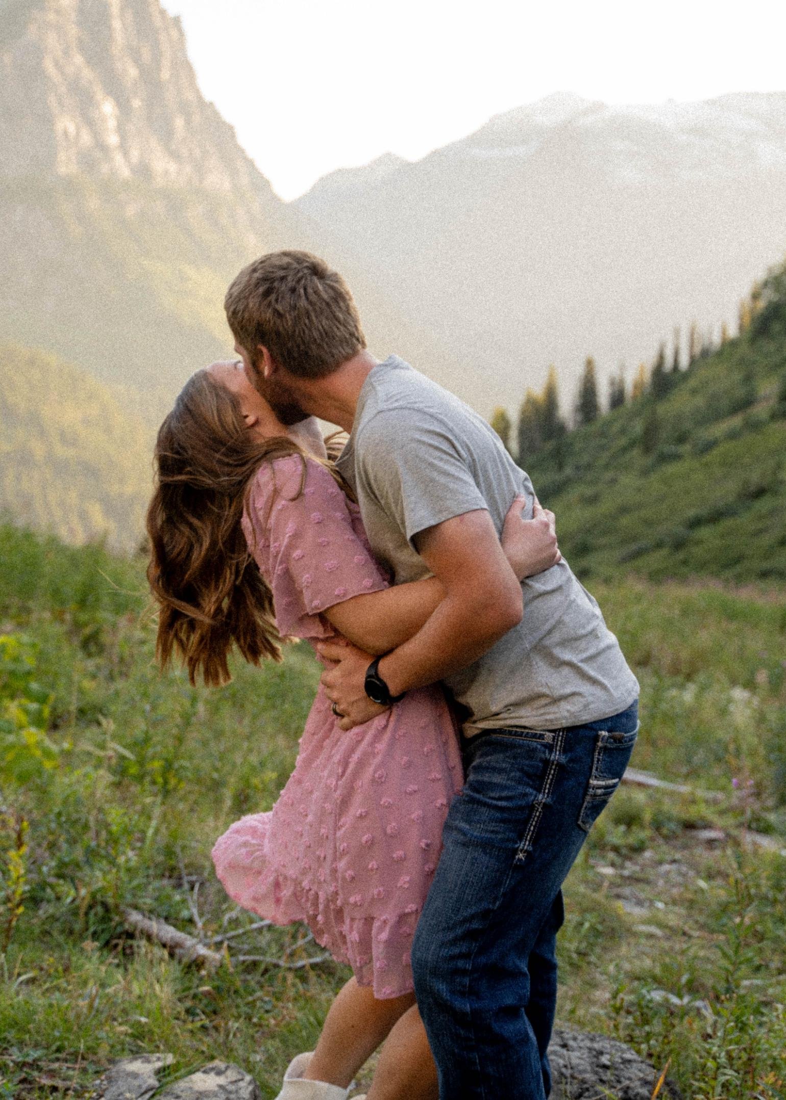 Couple kissing in a meadow in Glacier National Park, Montana, with the man gently dipping his partner, captured during a couples photoshoot