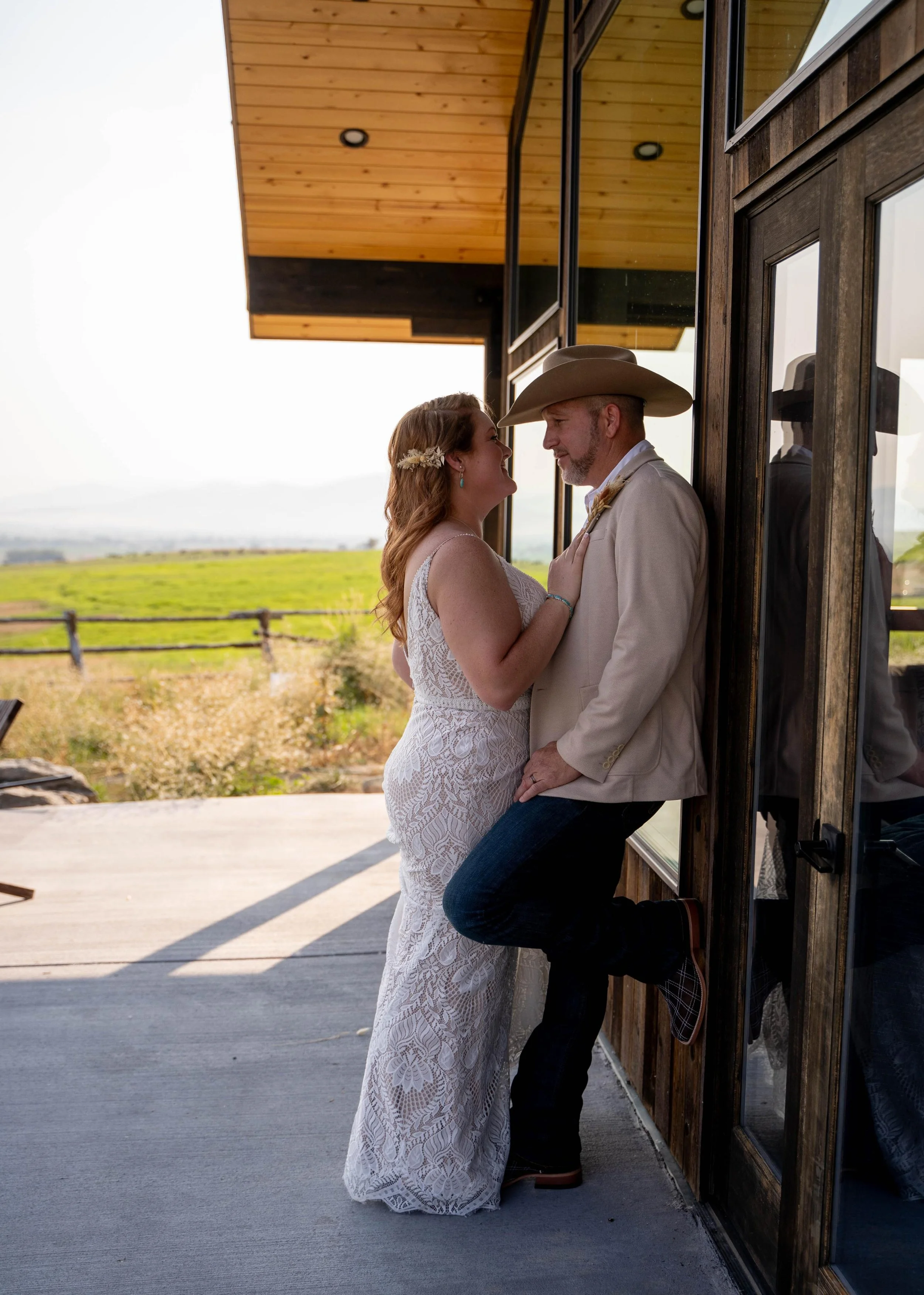 Bride leaning close to the groom outside a rustic cabin in Flathead Valley, Montana, captured during a wedding photoshoot.