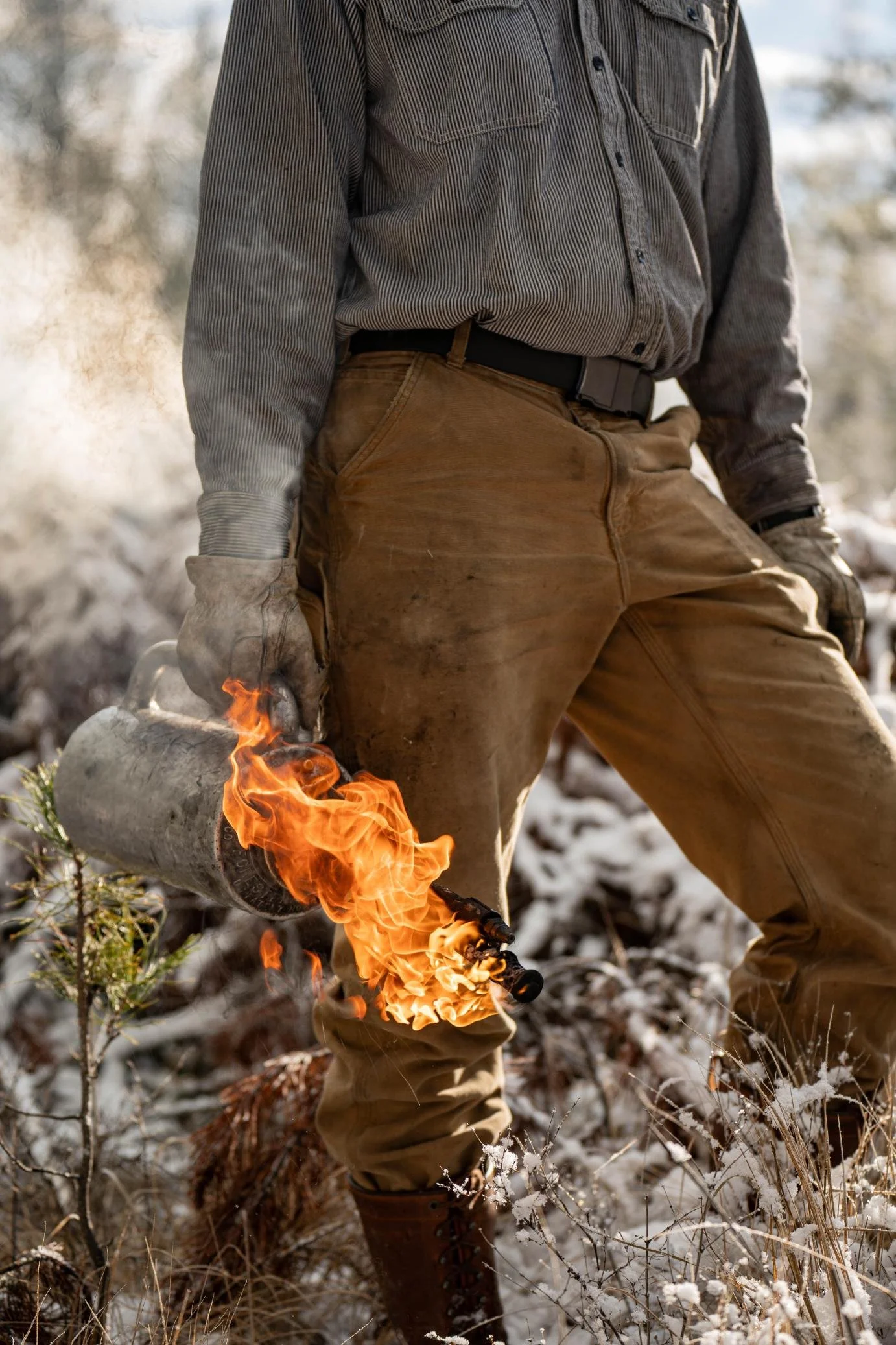 Front-side view of a man holding a blowtorch with a full flame, captured during the Apogee Belt field test photoshoot in Northwest Montana.
