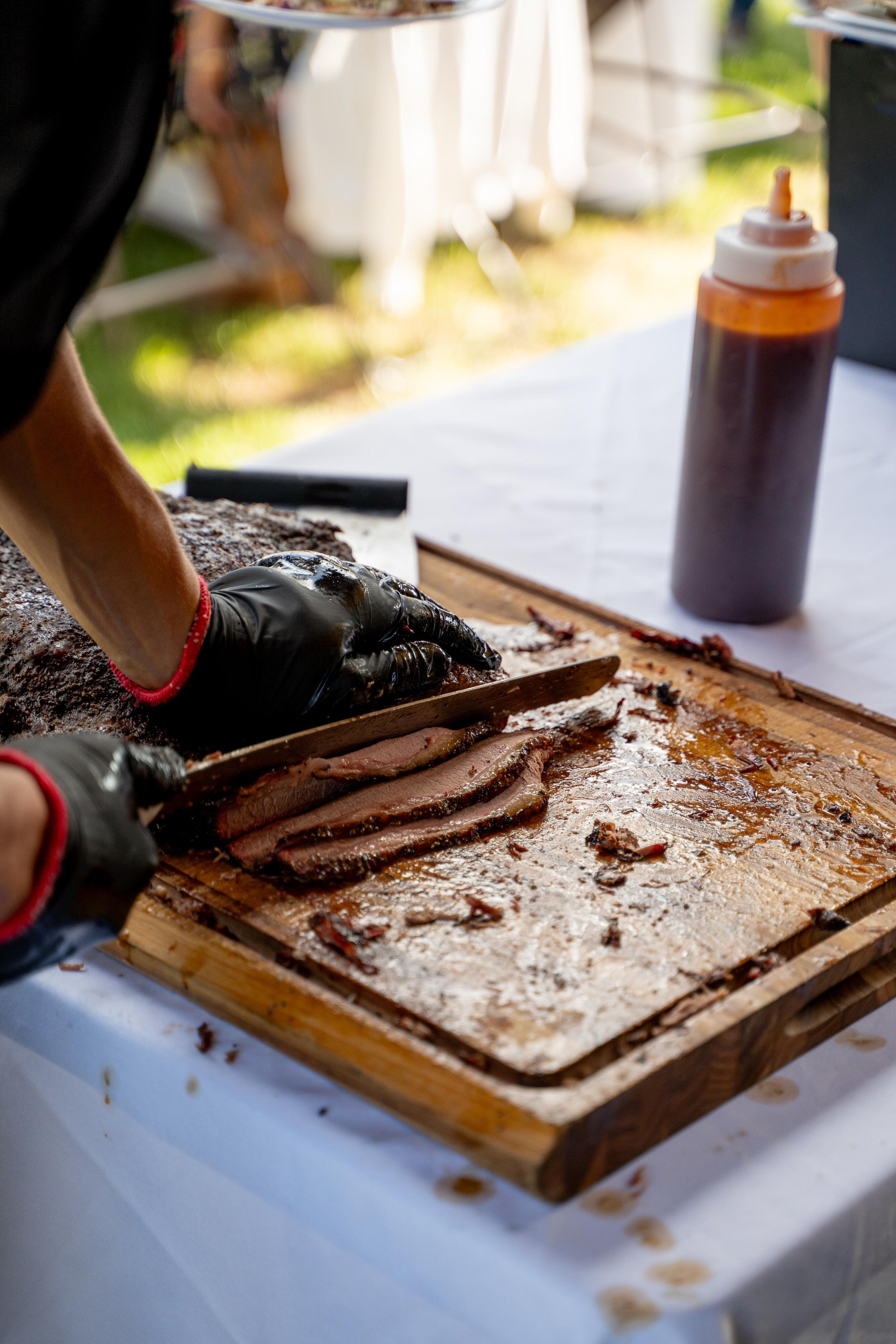 Close-up of a person slicing smoked barbecue brisket during a Montana Longhorn Ranch photoshoot, highlighting the texture and juiciness of the meat