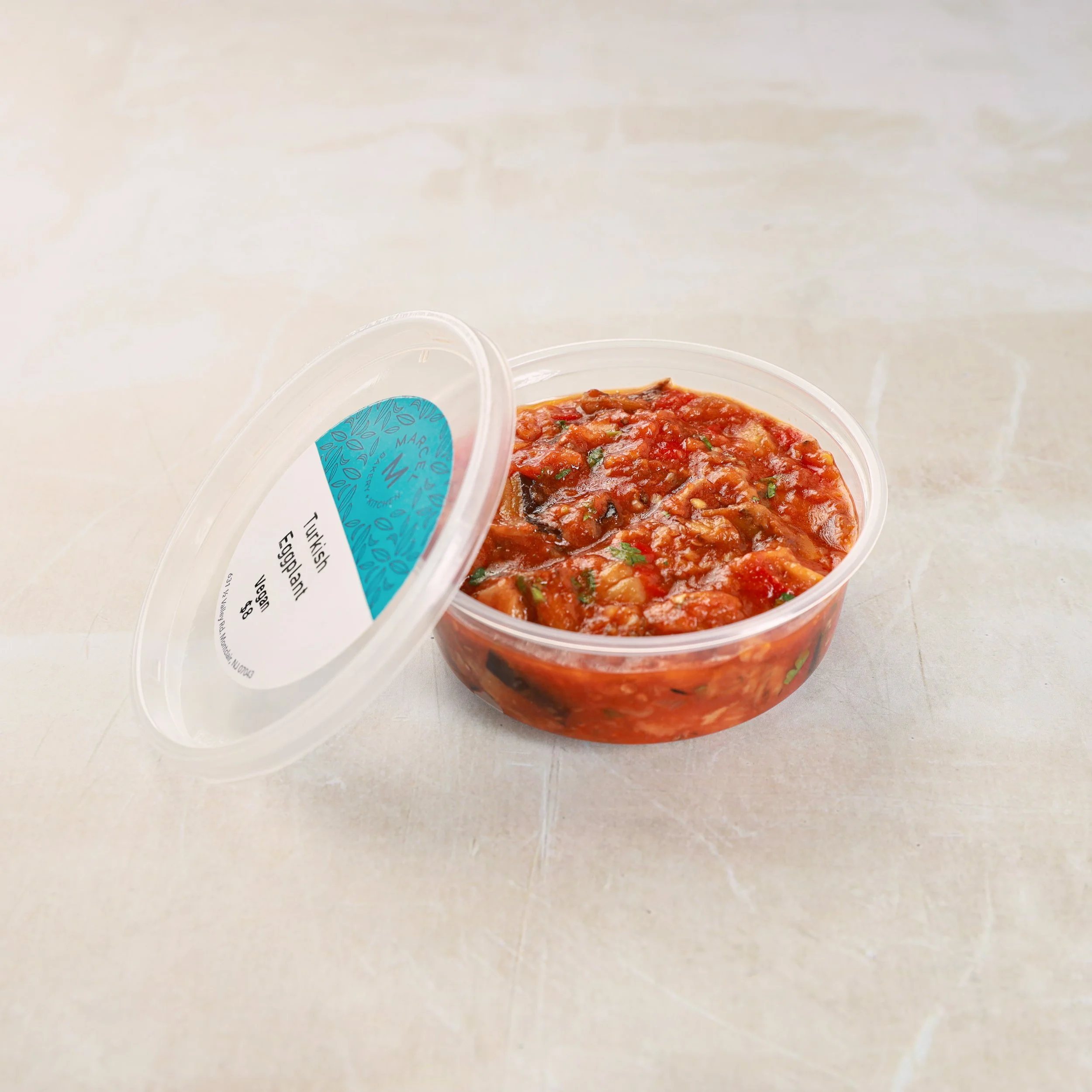 A plastic container of vegetable stew with a blue label and white background