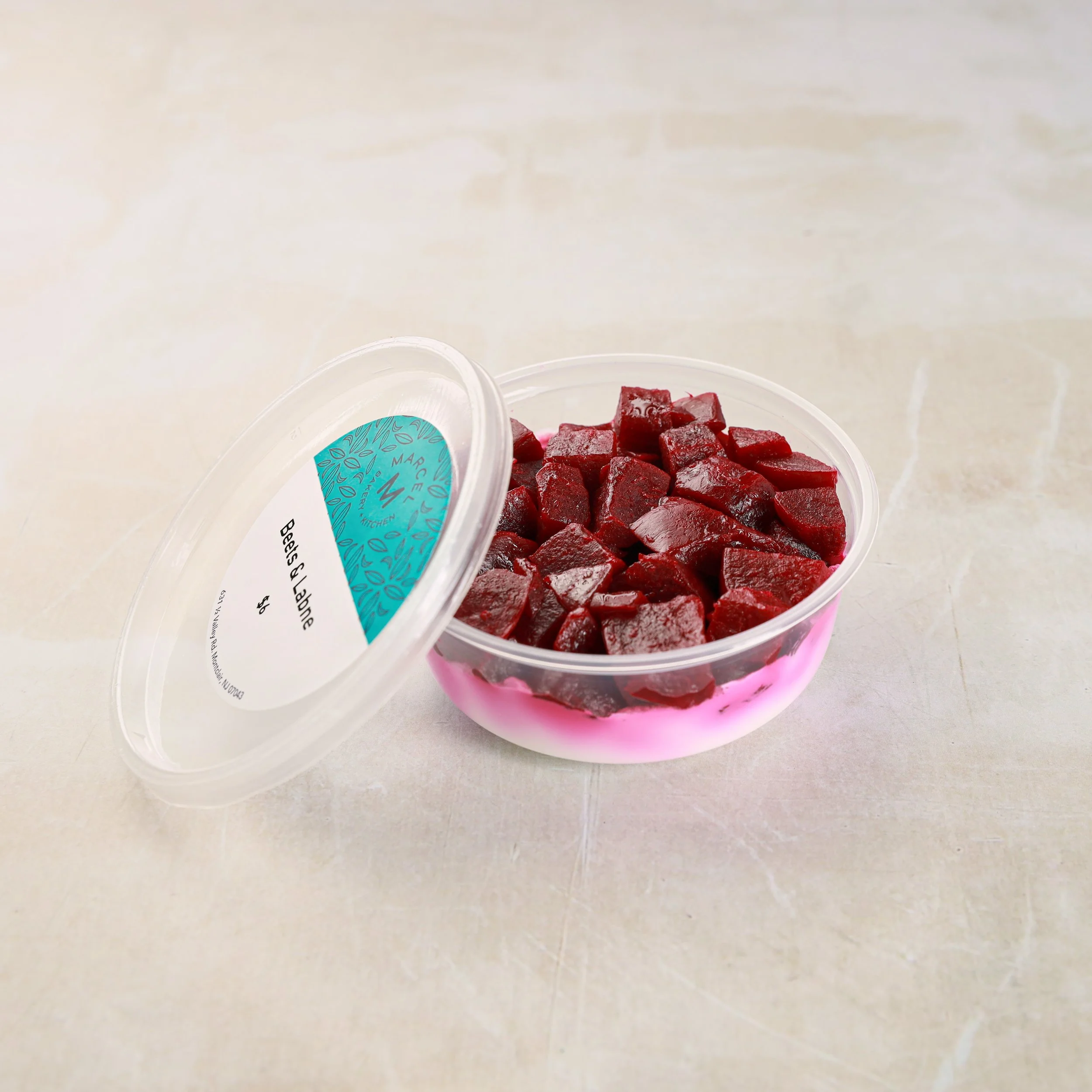 A clear plastic container of cubed red beets placed on a light-colored surface.